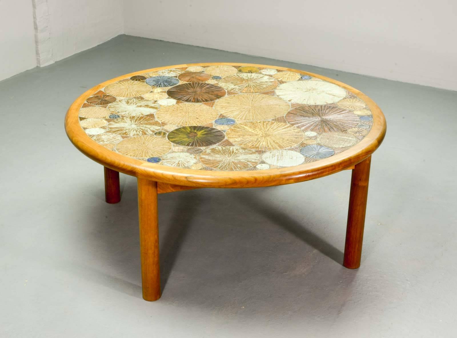 Stunning Danish coffee table by Tue Poulsen and produced by Haslev in the 1960s. The frame is made out of solid teakwood. The artistic table top is decorated with sunburst ceramic circular tiles in various sizes, set in a beautiful earthtone color