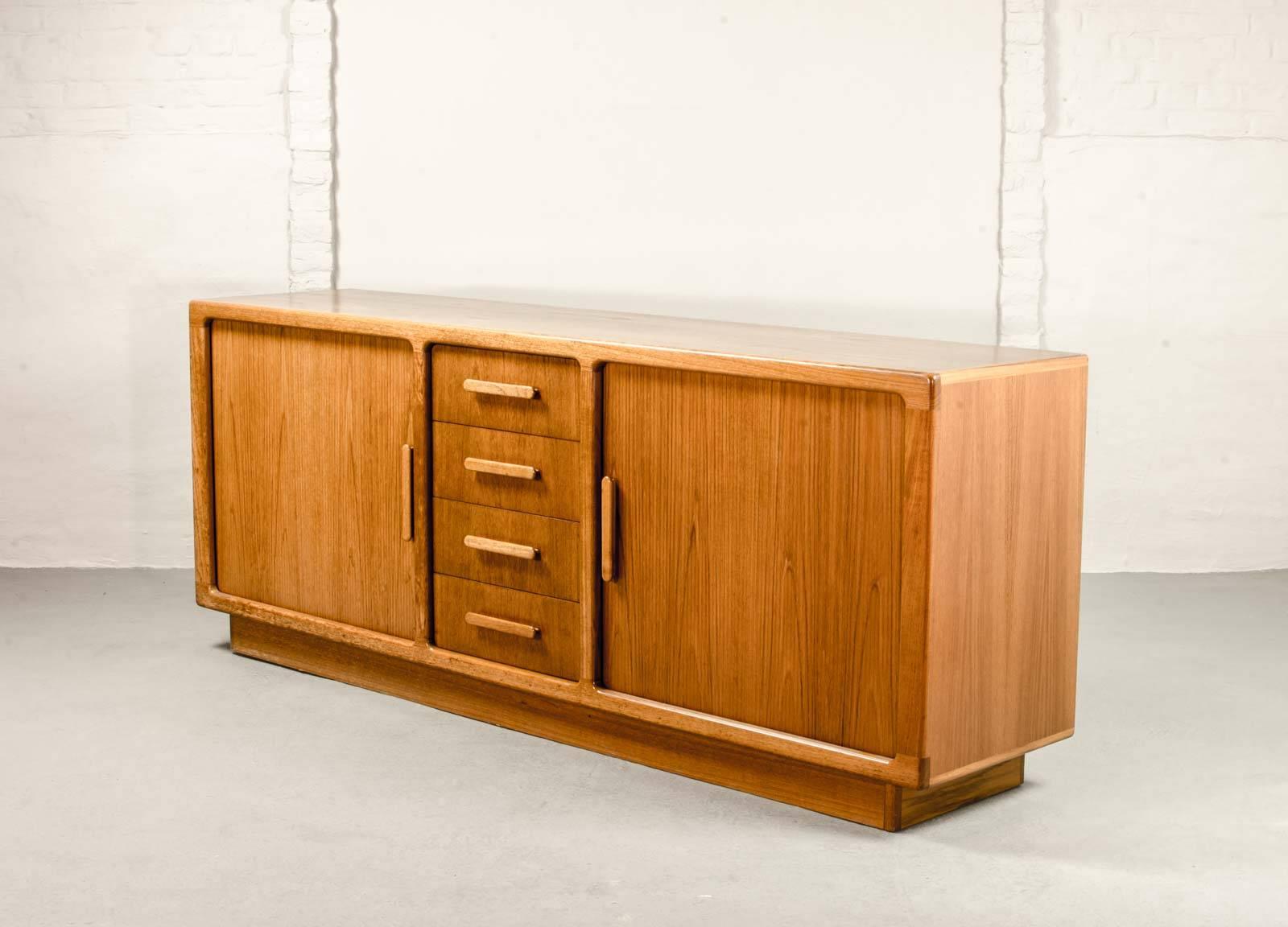 Beautiful credenza designed by Johannes Andersen and constructed in Denmark by CPC Silkeborg in the 1960s.
This teak sideboard features elegant tambour doors and contains four drawers and two storage units. This sideboard/credenza is in absolute