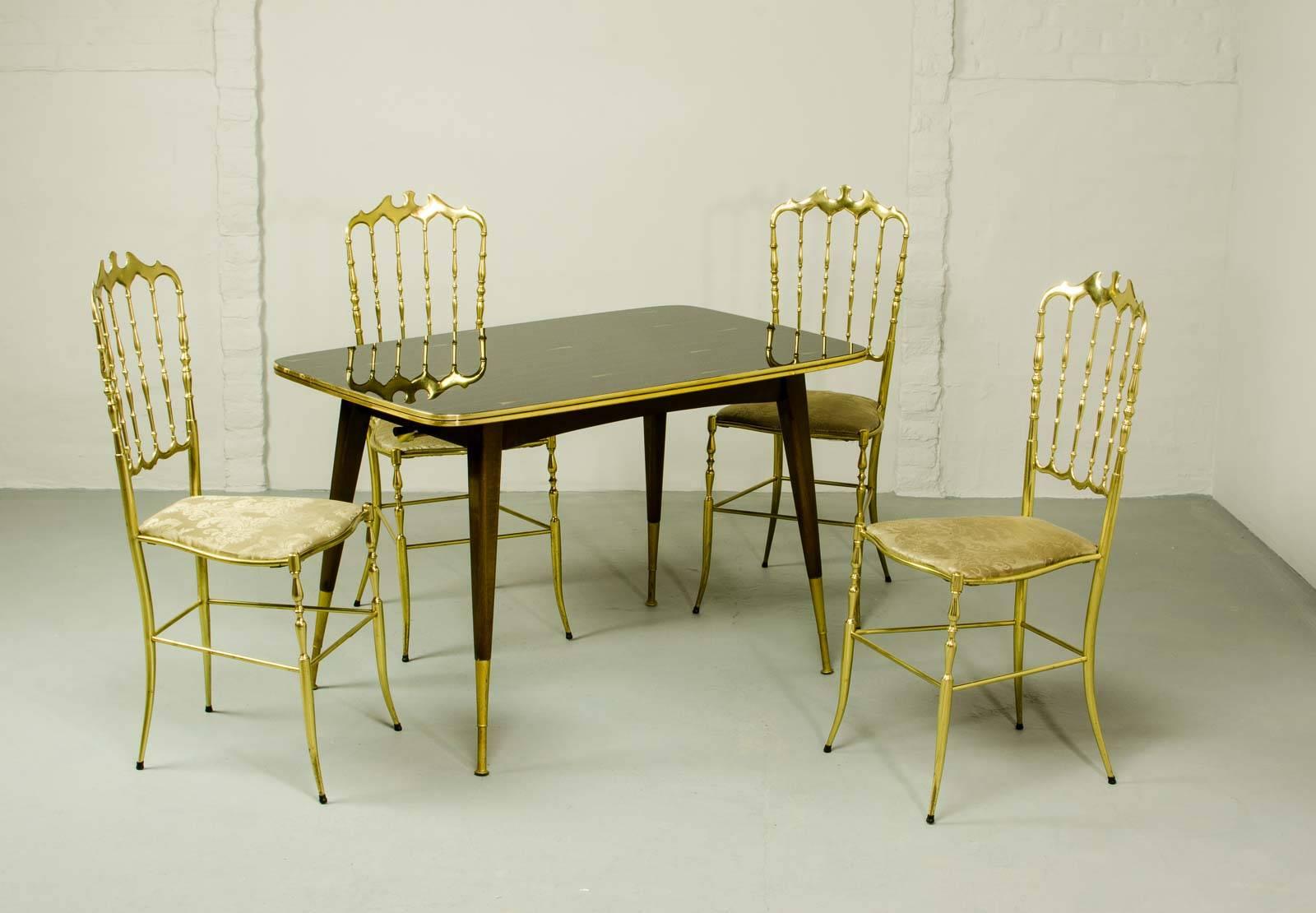 Very elegant set of four Midcentury Italian brass Chiavari spindle back chairs and matching stylish game / card table. The polished brass chairs with padded seats upholstered in golden gobelin fabric are designed by Giuseppe Gaetano Descalzi for