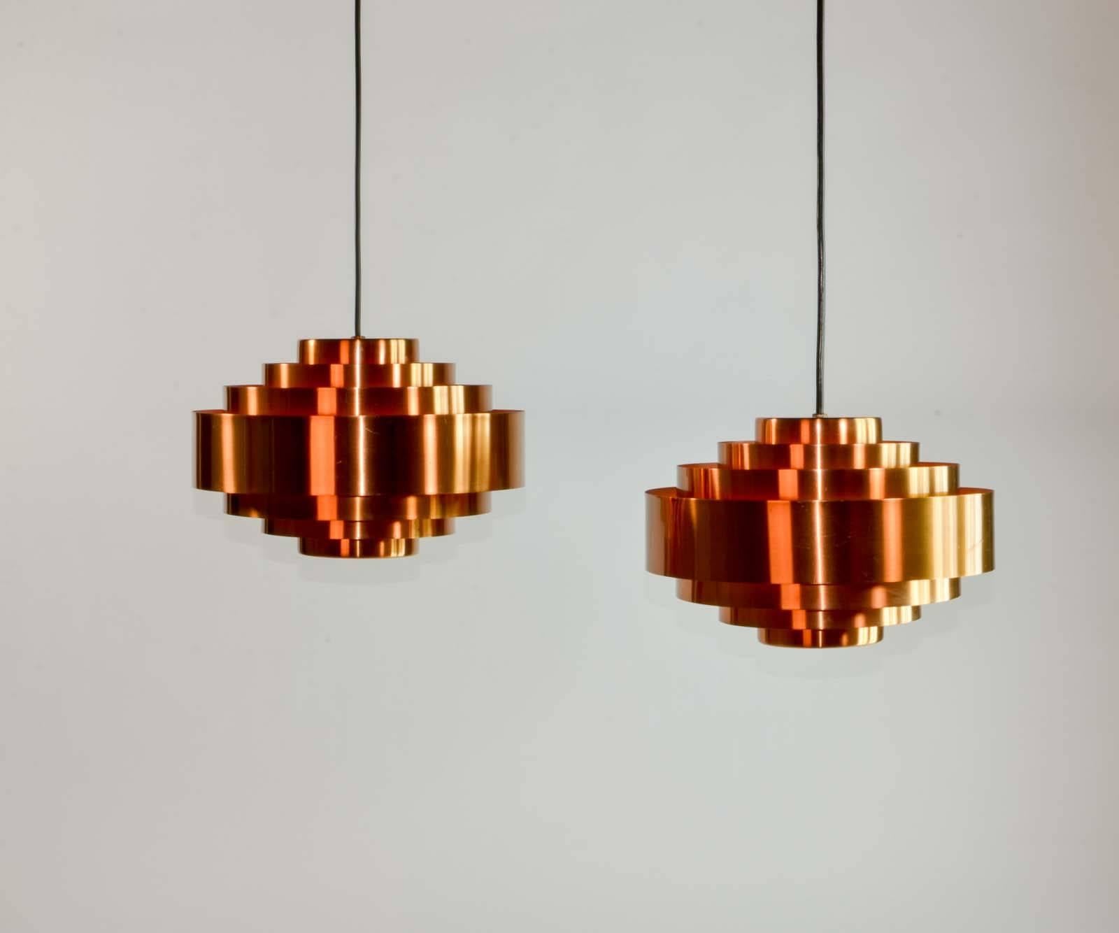 This solid copper pair of 'Ultra' pendants was designed by Jo Hammerborg for Fog & Mørup in the very early 1960s. This version shows an orange inner and consists of seven rings. It is closed towards the top and at the bottom it has a (rare) diffuser