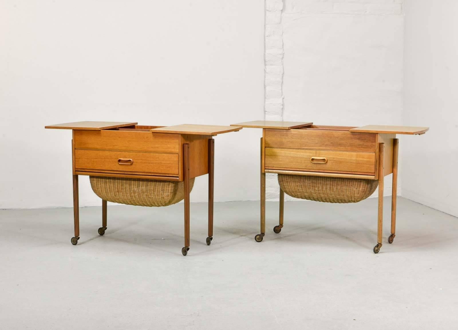 This great pair of solid teak Scandinavian sewing tables were designed in the 1960s and feature a handwoven cane basket with inside drawer for sewing implements. Although these very lovely pieces were designed to house sewing tools, they perfectly