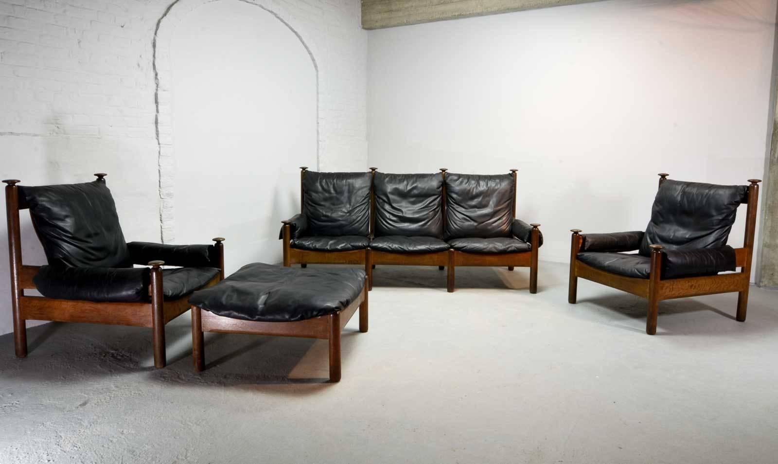 Sturdy midcentury soft black leather Scandinavian sofa set produced in the 1960s in style of the Danish designer Arne Norell. The sofa set features an oak wooden base with knobs and black leather upholstery which is in an overall good condition. The