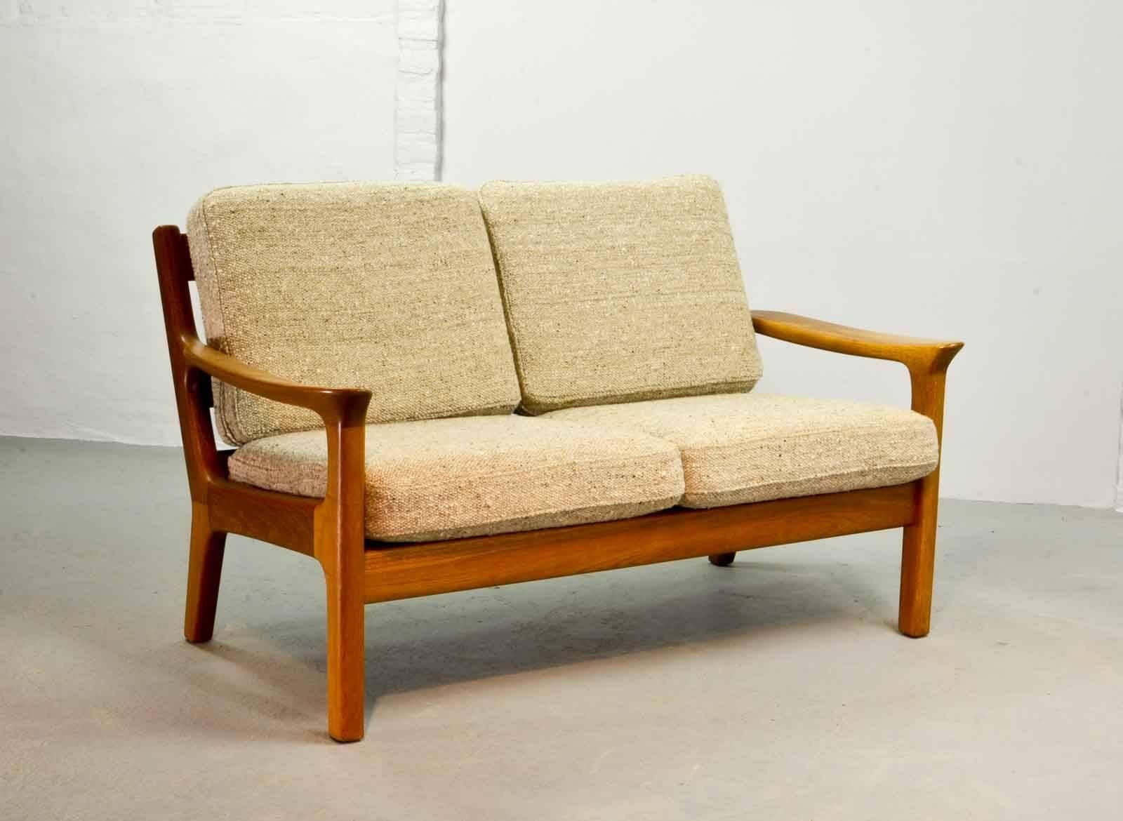 Two-seat sofa in solid teak and cushions designed by the Danish designer Juul Kristensen and manufactured by Glostrup Furniture Factory in the 1960s. The cushions are upholstered with a sandy colored high quality fabric. Both the teak wooden frame