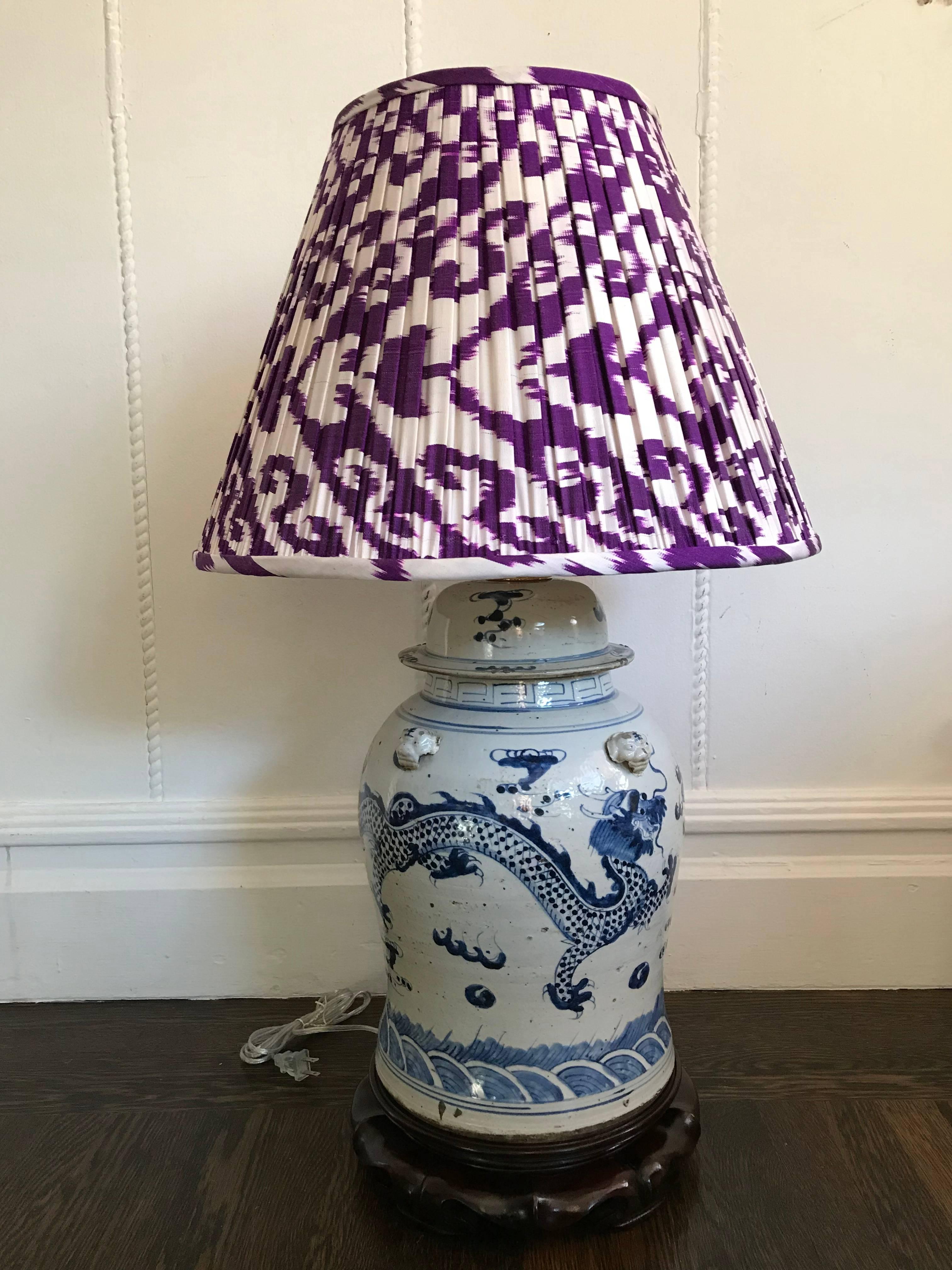 Antique hand-painted blue and white chinoiserie ginger jars that have been newly converted to lamps. Hand-carved wooden bases. Custom violet silk Ikat pleated lamp shades.