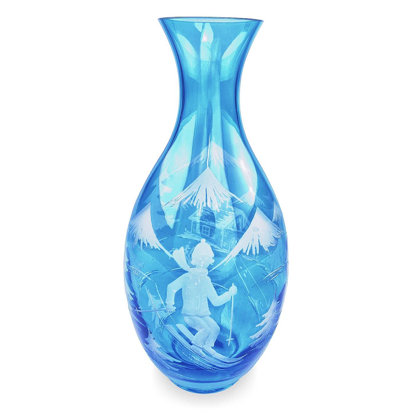 
Handblown crystal vase/lantern in blue glass with a winter scene. Hands-free engraved with skier, lodge and trees all around. Shown in blue glass and can be manufactured in many other colors. Sofina crystal was established in 2013 in