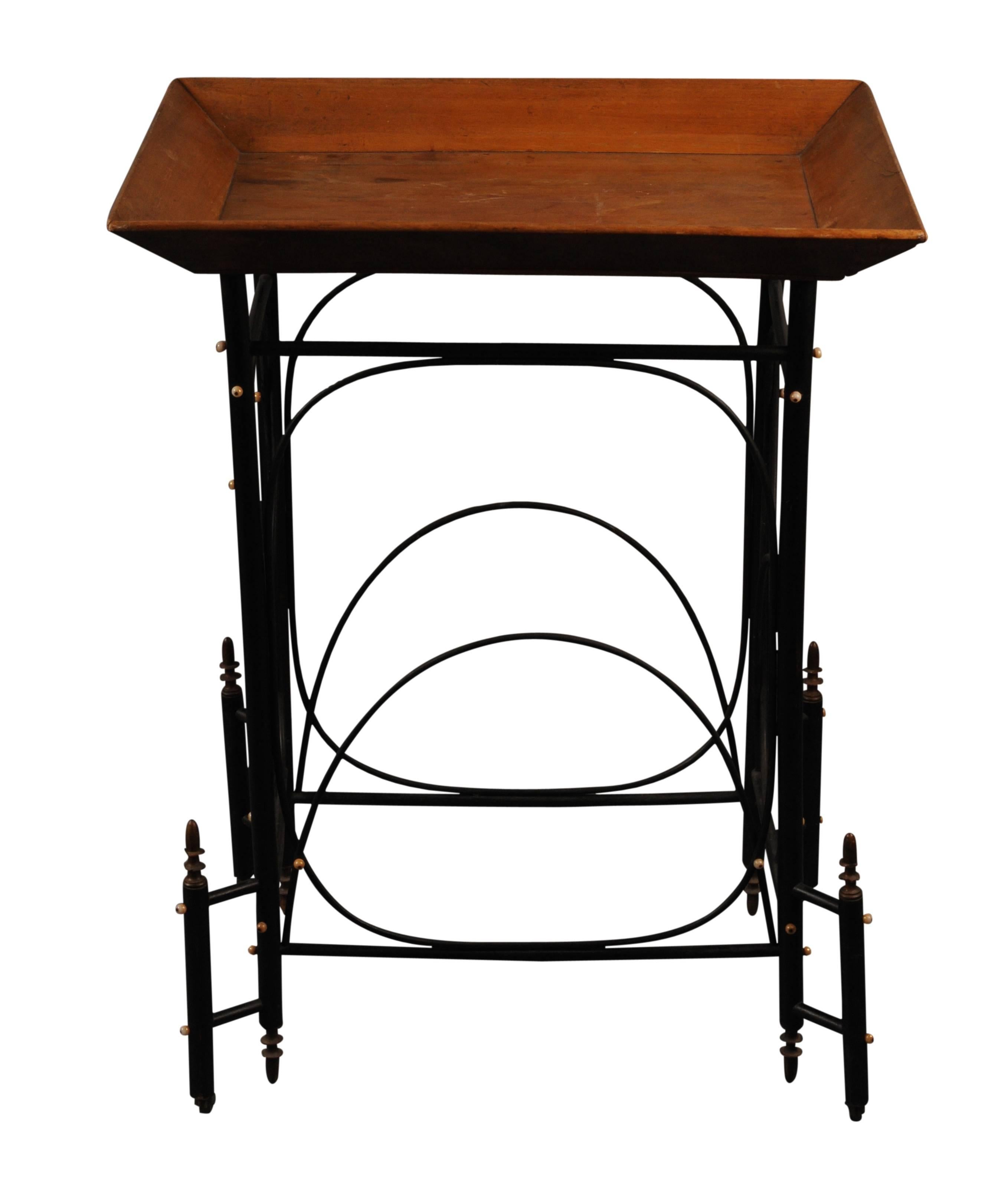 The rattan-based and with ebonized surface raised on castors and with glass cabochon decoration supporting a fruitwood tray top.
 