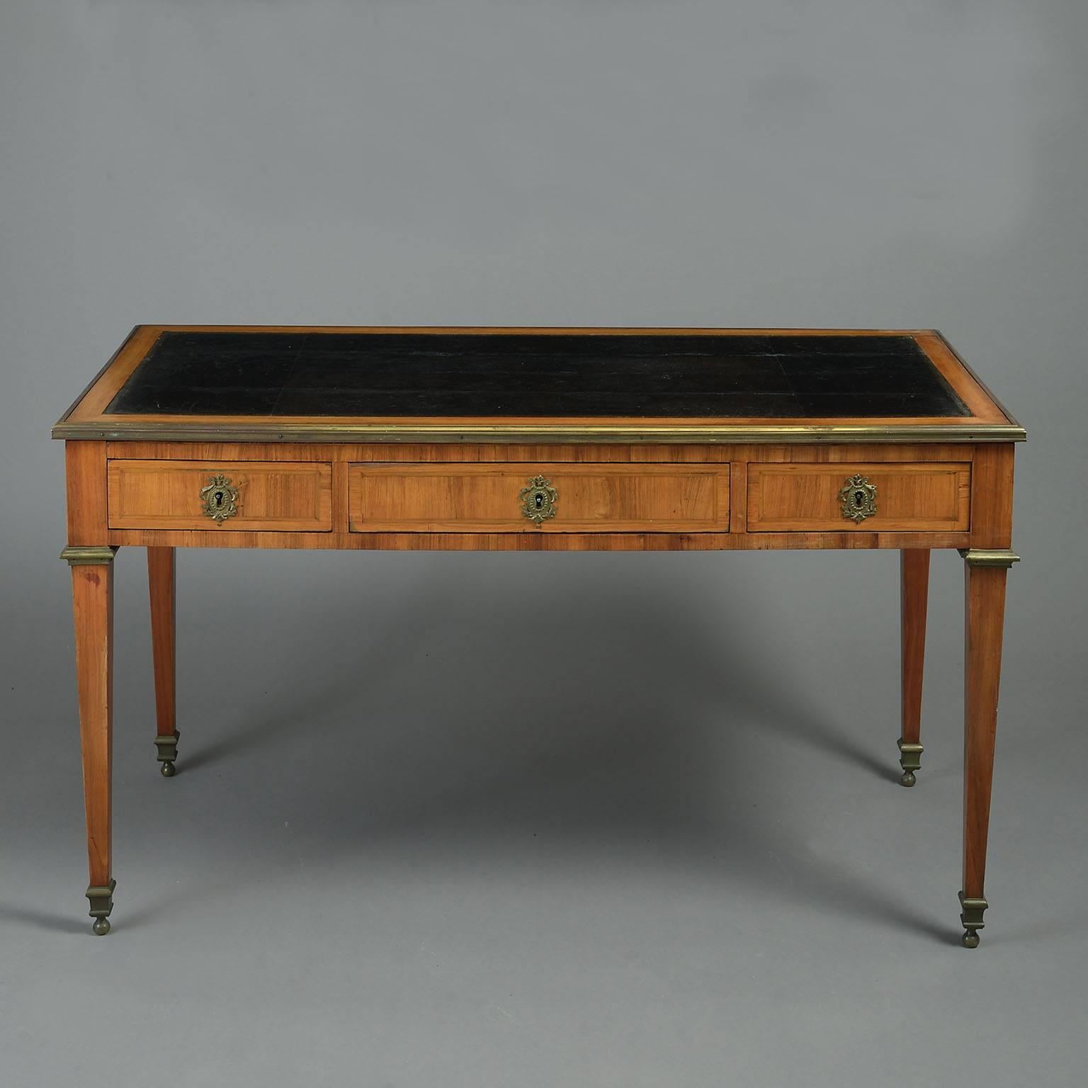 The black leather inset top with cross-banded border and brass edging over a frieze veneered on all sides with cross-banded panels and having three raised on square tapering legs with brass moulded collars and ball feet. 


circa 1780

Depth: 64cm /