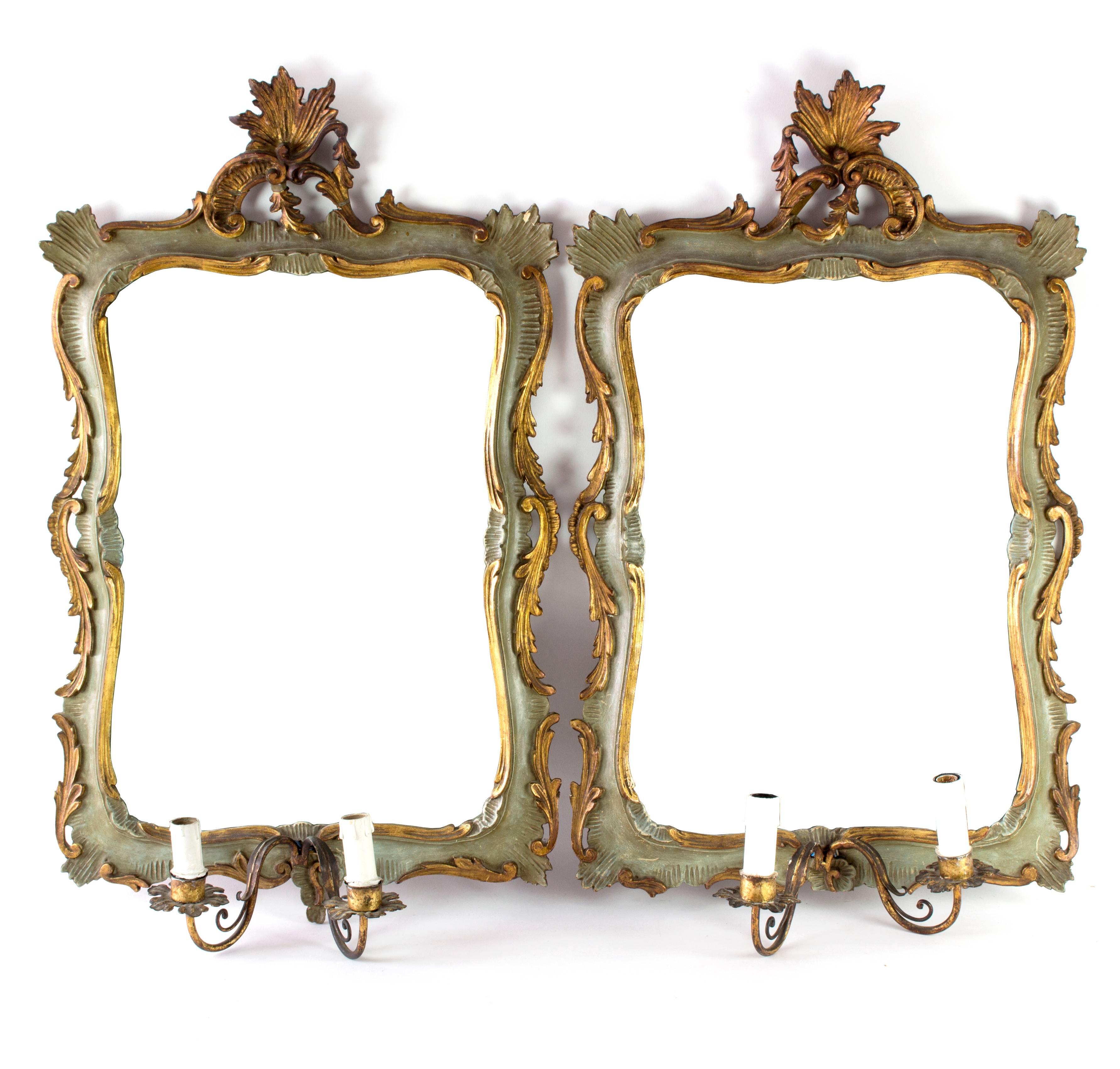 The shaped rectangular plates contained within frames of carved, painted and parcel-gilt Rococo scrollwork, with pierced crestings and each with two gilt toleware candle-branches, hollow to allow for wiring.