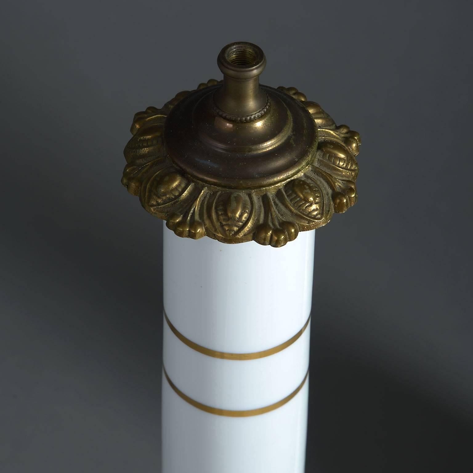 The mallet shaped body decorated with gilt bands and wide Greek-key on a milk-white ground and raised on a patinated brass base.

The price includes wiring.
