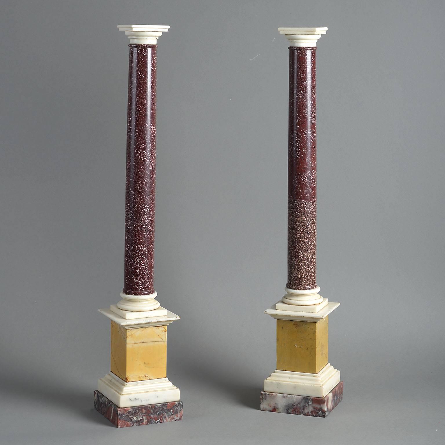 Of Tuscan form, the Porphyry column shafts surmounted by white statuary marble capitals, standing on white statuary marble bases and raised on Siena marble plinths with statuary marble mouldings. 

Measures: Width 11 cm / 4.25''
Height 59 cm /