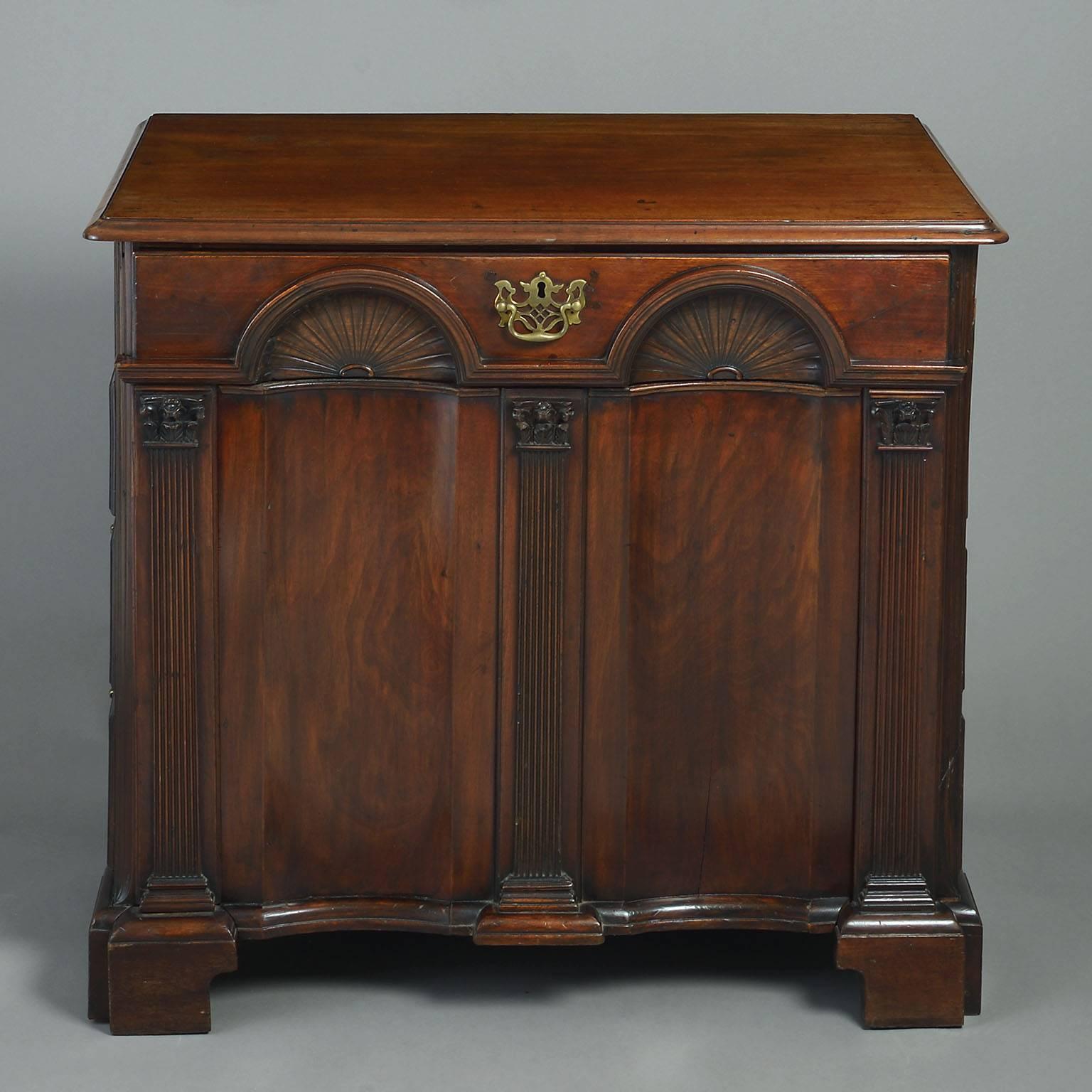 The rectangular moulded top above a double inverted shell-carved front flanked by Corinthian column pilasters, sliding forward to reveal a tooled leather writing surface and enclosing eight pigeonholes; one side with a cupboard door simulating three