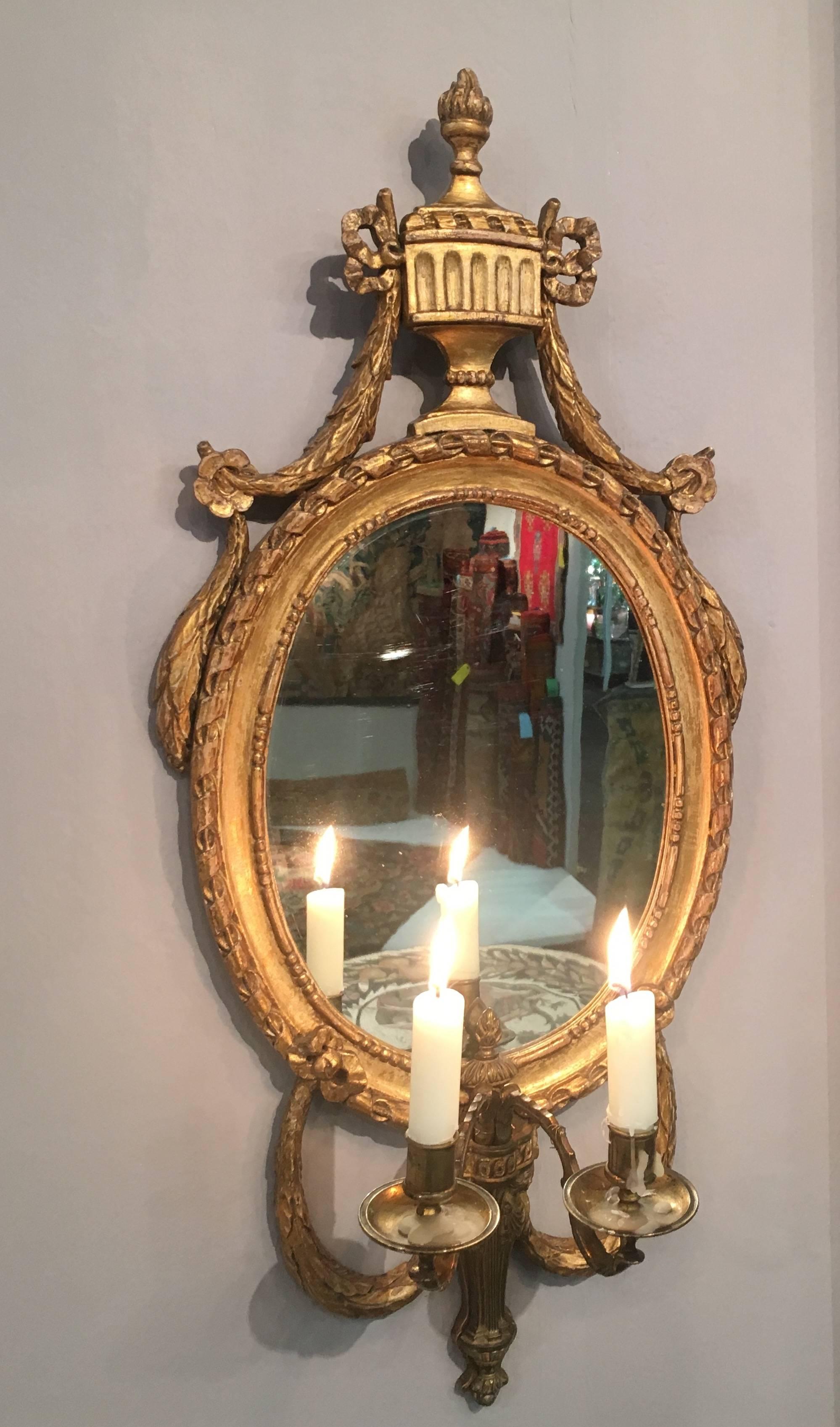 Almost certainly Swedish, the oval mirror plates with ribbon decorated surrounds festooned with laurel garlands surmounted by flambé urn crestings, each with two gilt-metal candle-arms supported by addorsed caryatids. Currently wired for electricity