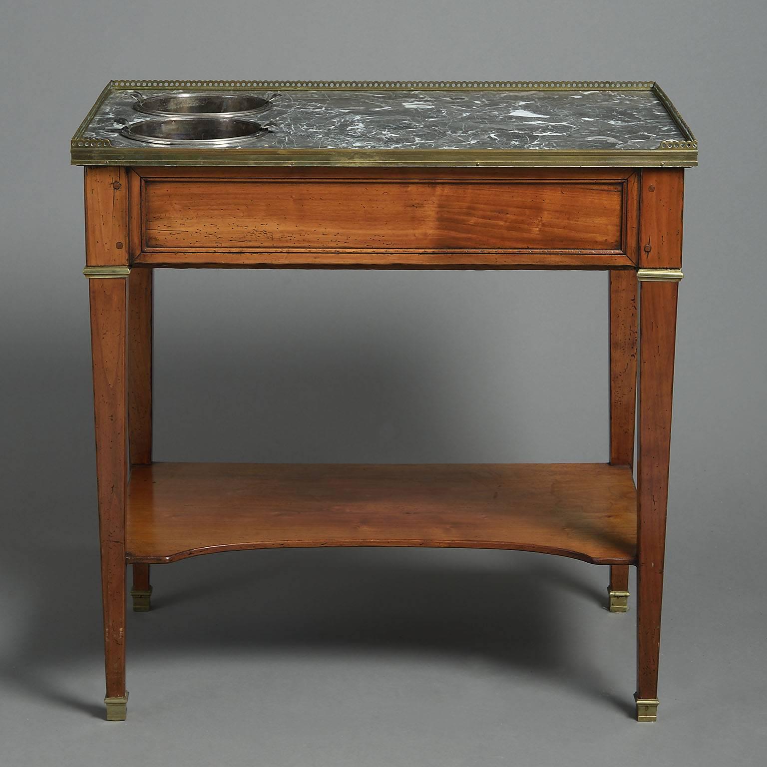 In the Louis XVI style, the rectangular grey marble-top pierced to take two silver plated wine-coolers, the frieze with a single drawer to one end and raised on square tapering legs with brass collars joined by a shelf stretcher.
Stamped with an