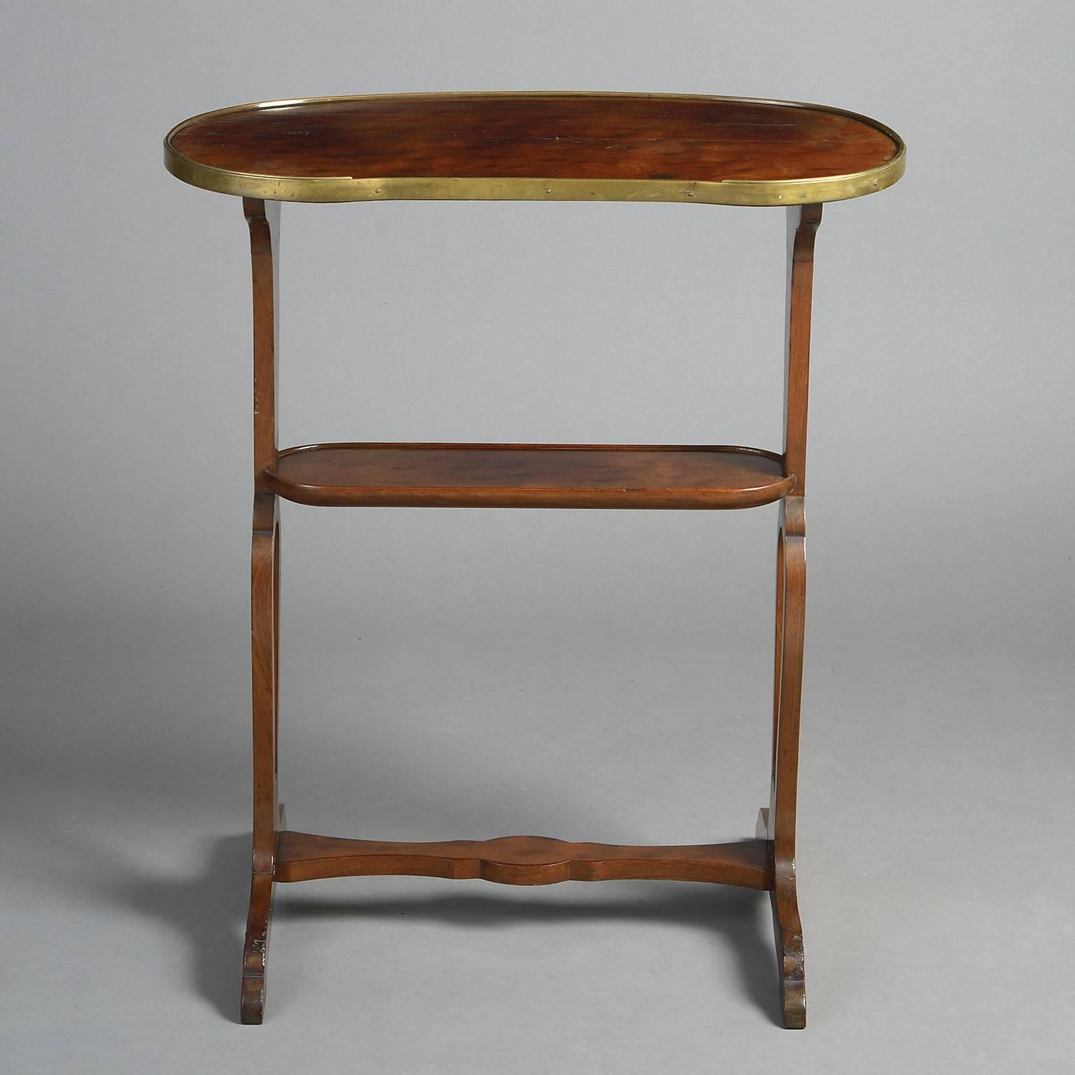 The kidney-shaped top of highly figured “plum pudding” mahogany with brass edging raised on pierced trestle supports with lower tier. 

Stamped Escalier De Cristal PARIS.
 
