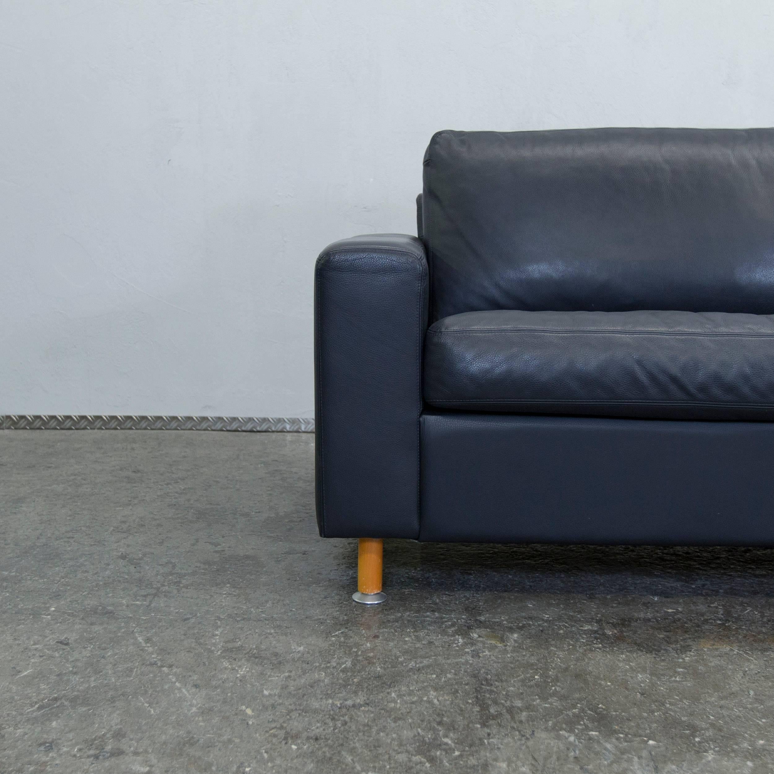 Machalke leather three-seat sofa in dark blue made in Germany. Great accent by brown feet.
