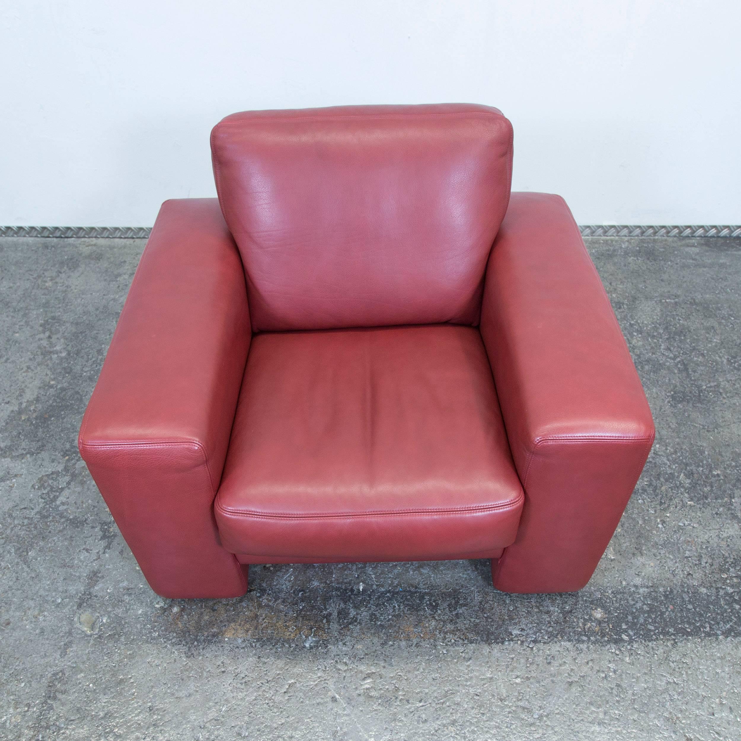 Red colored original Koinor designer leather armchair in a modern and minimalistic style, designed for pure comfort.