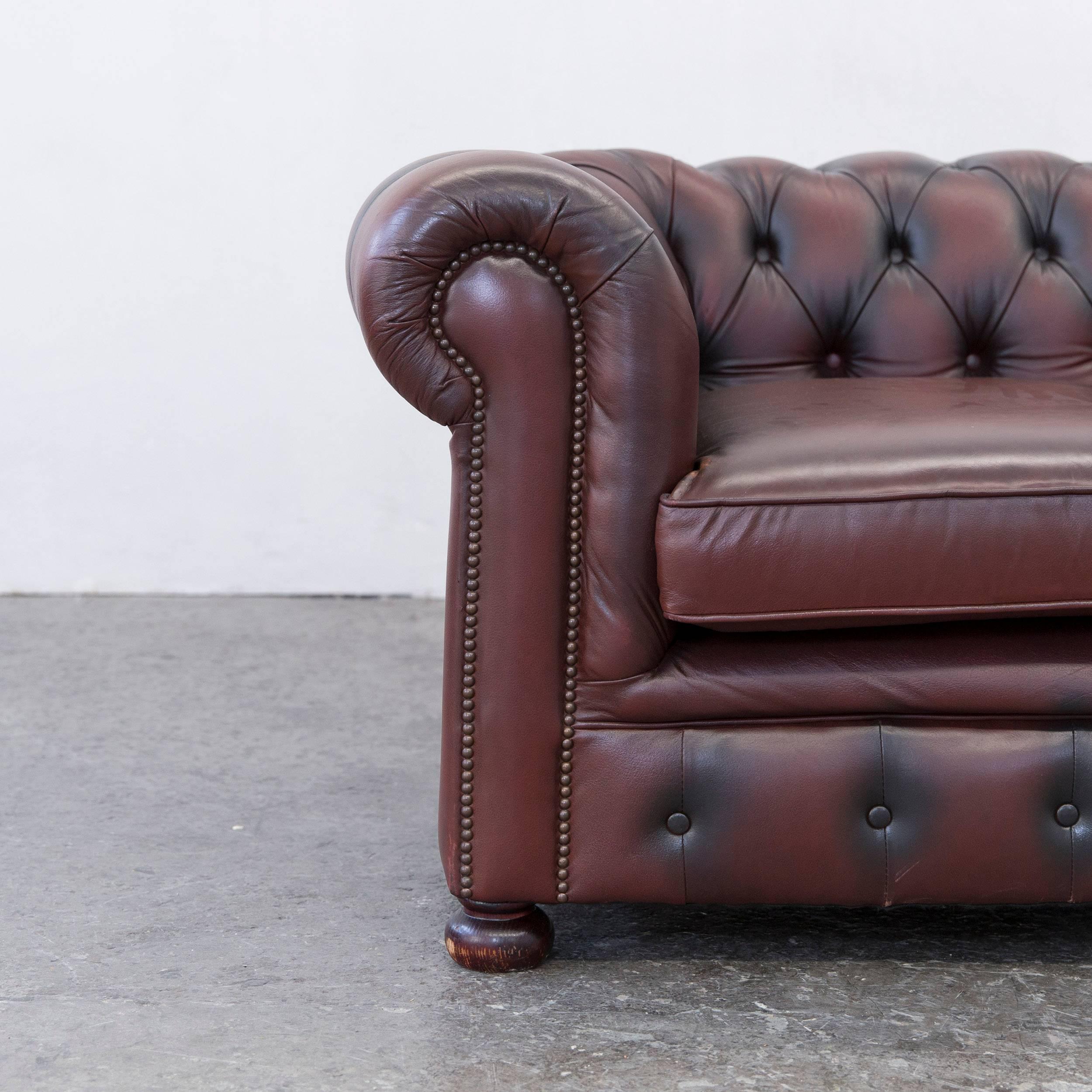 Authentic chesterfield two-seat couch in brown-red colored leather.