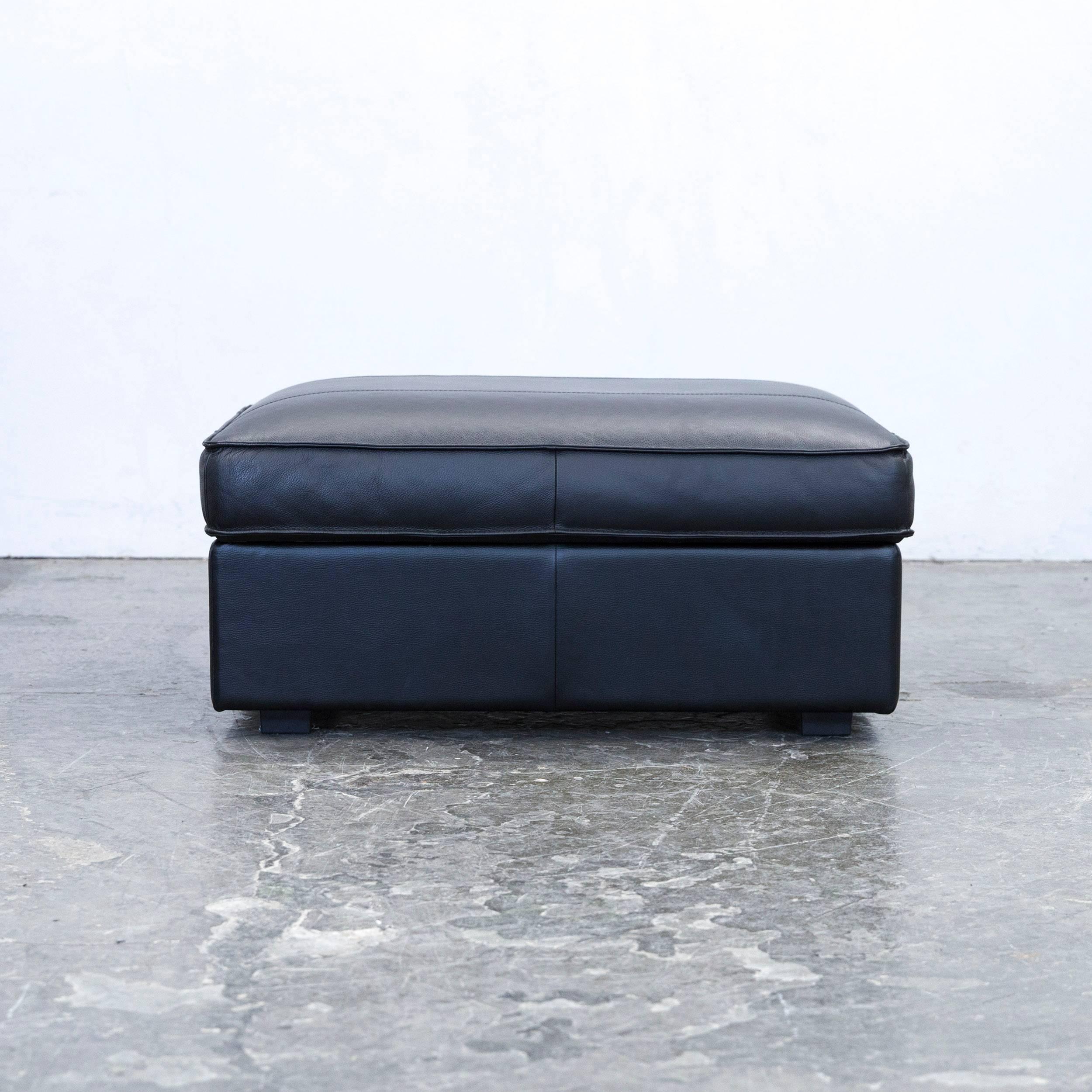 Black colored designer leather footstool, in a minimalistic and modern design, with a convenient function, made for pure comfort and flexibility.