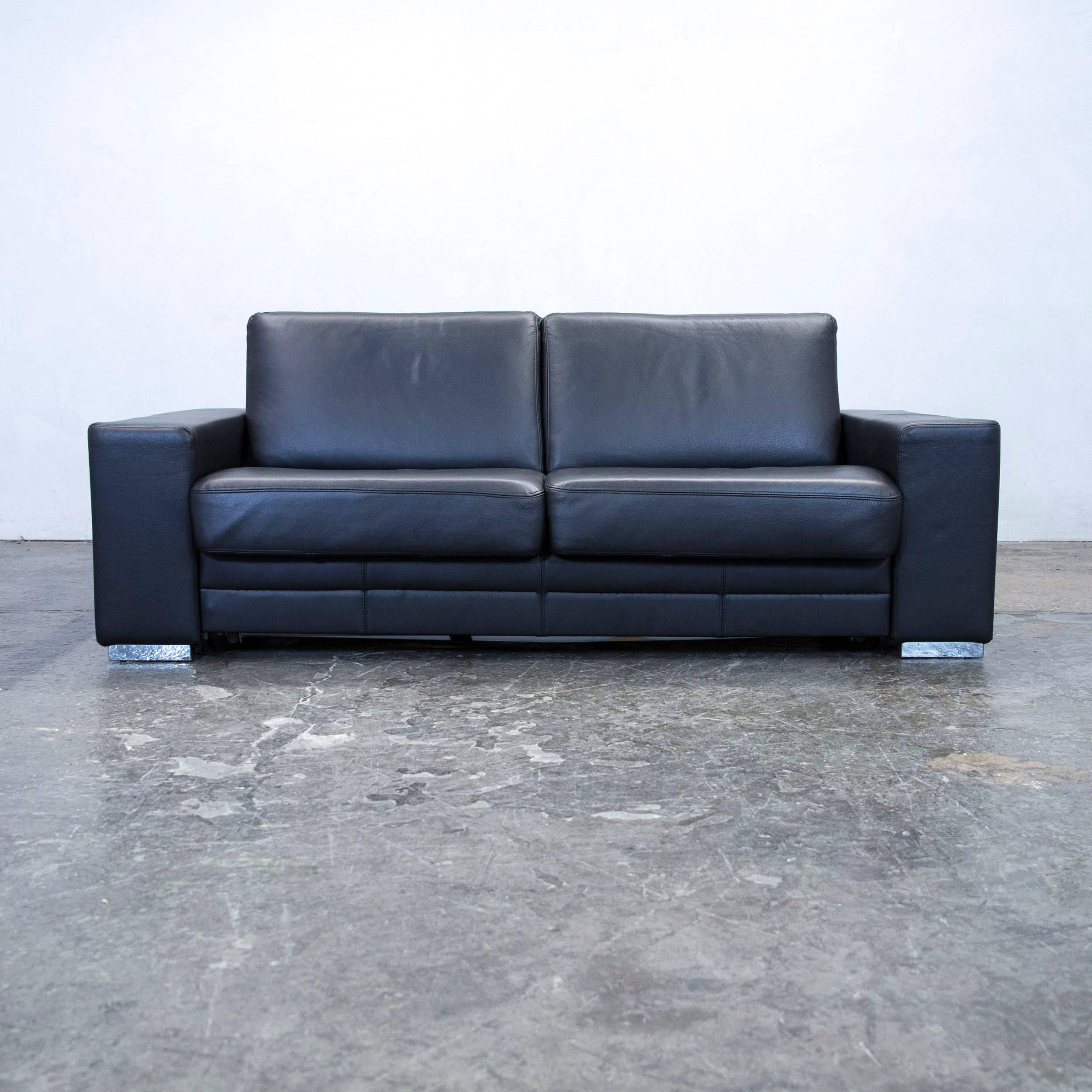 Black colored designer leather sleepsofa and footstool, in a minimalistic and modern design, with a convenient function, made for pure comfort and flexibility.