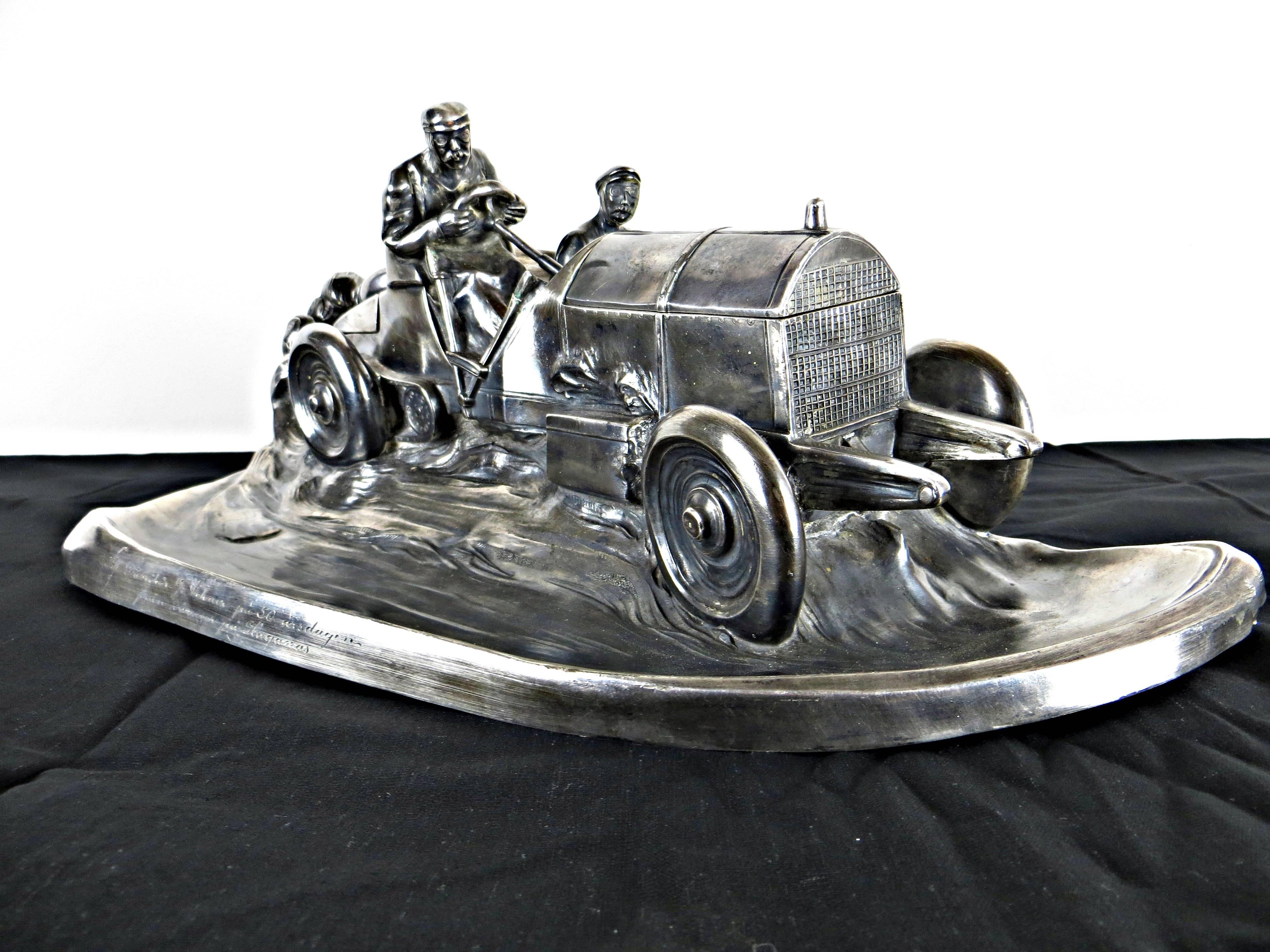 Tin plated, in the form of a speeding early open race car with driver and riding mechanic, the hinged hood revealing inkwell and with hinged trunk, 16 ins long. Lower with a dedication in Swedish. Rare and wonderful piece by the Württembergische