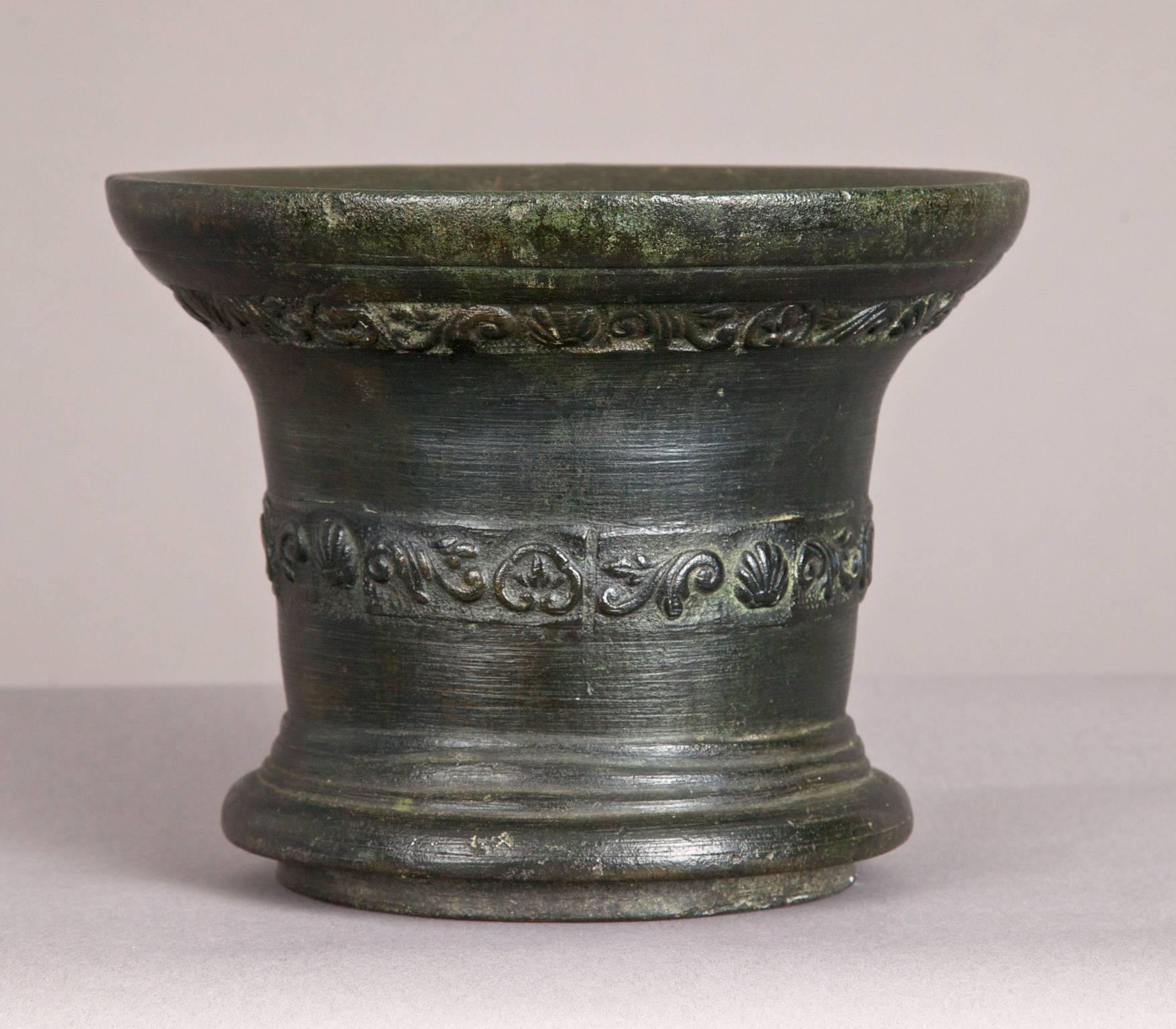 Mid-17th century lead bronze mortar. English, Whitechapel, City of London, circa 1630-1650

The deep rimmed mortar cast with a scrolling floral pattern under the lip, the body with a further band of interlace centred upon scallop shells. From a