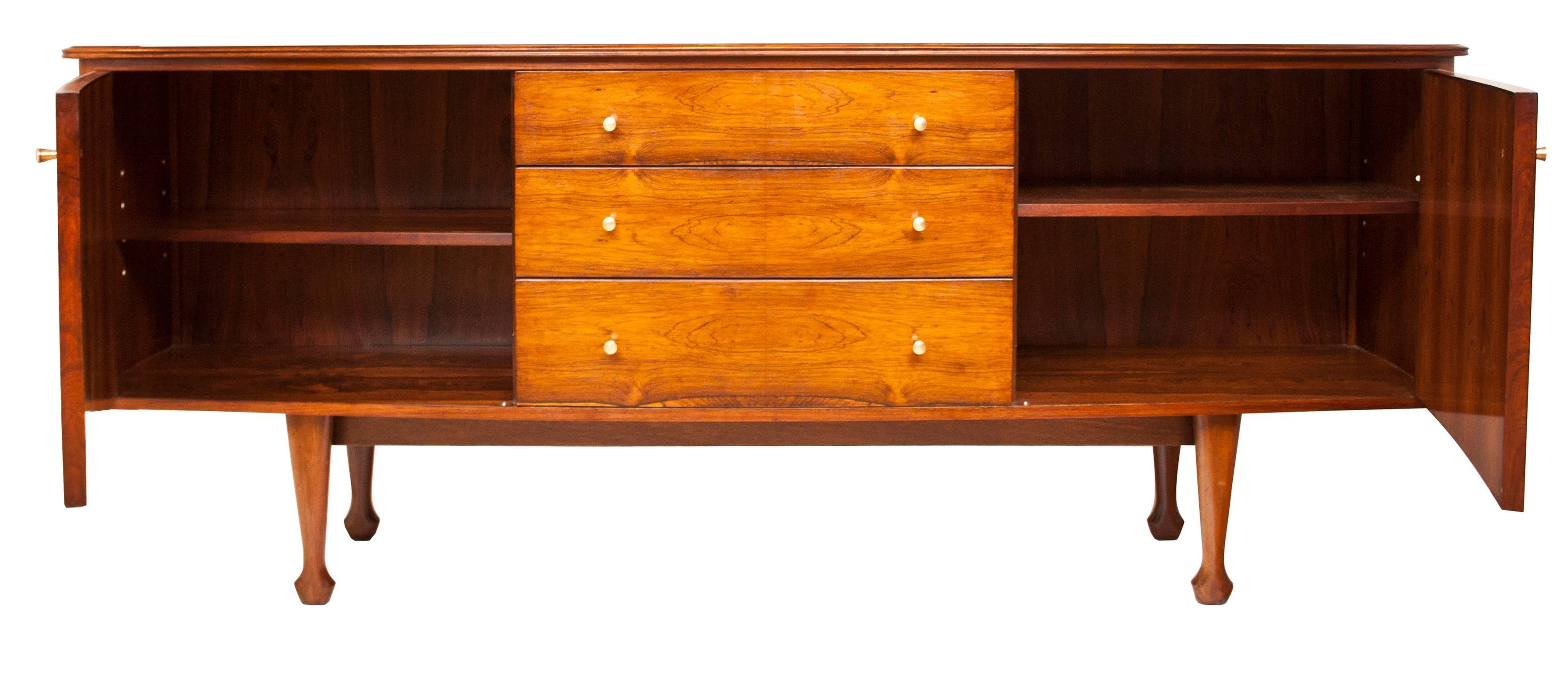 Indian rosewood sideboard designed by Andrew J Milne and retailed by Heals.
English 1960s of curved form with high quality veneers and brass handles.