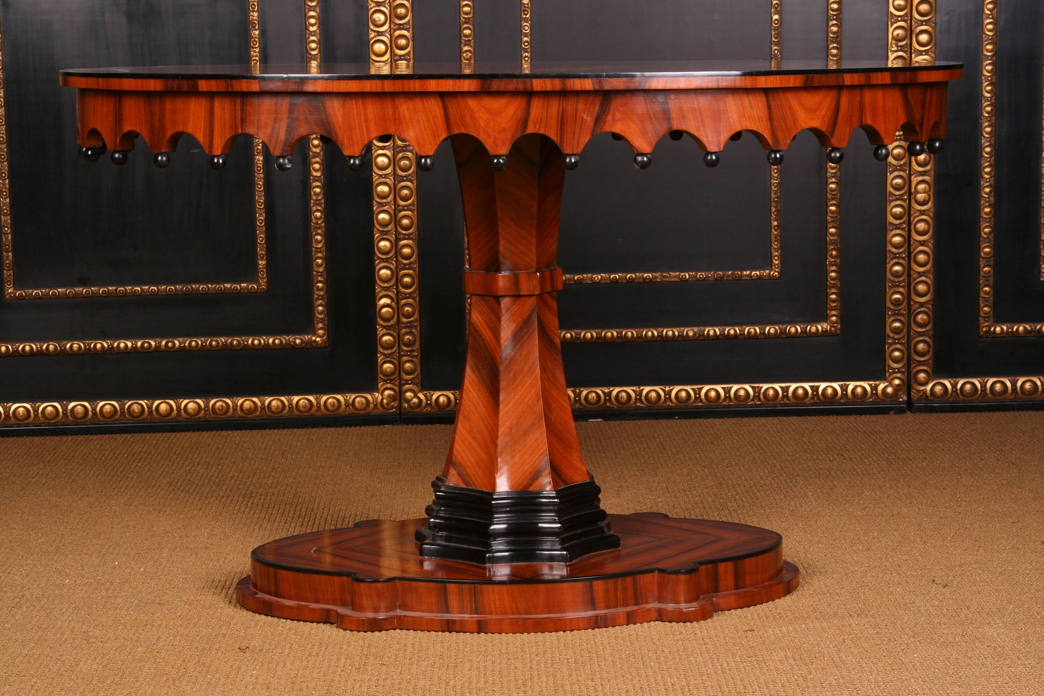 Exotic rosewood on solid wood. Oval curved and profiled base plate. Centrally rising, eightfold folded fan-shaped column, partly blackened. Gothic frame with protruding profile plate. This form is extremely rare. Patina and honey-colored veneer