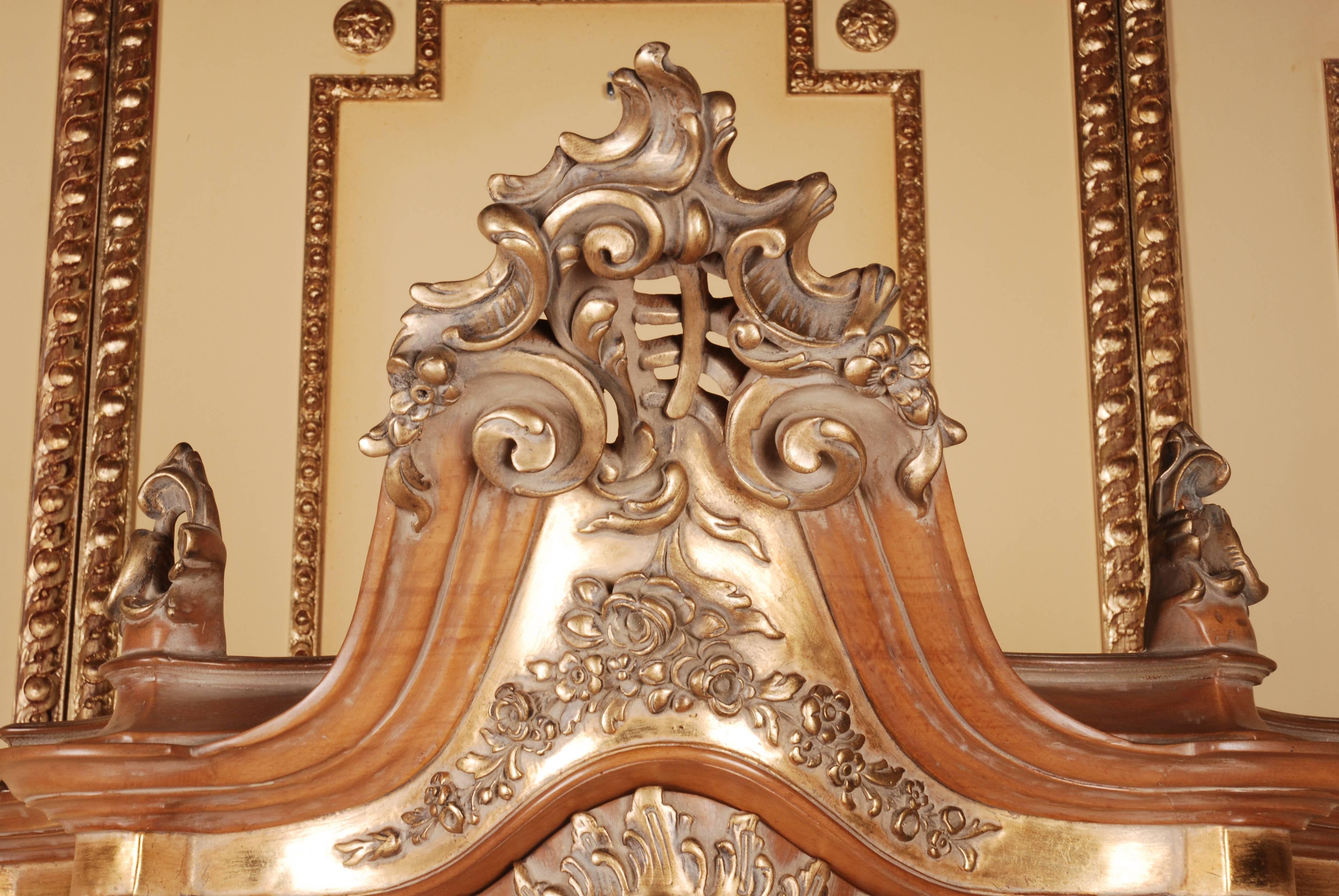 Solid beechwood, finely carved and polished, poliment gilded. High-rectangular, one-armed, cambered and three-glazed corpus on high, oblique, volute-like, curly feet, connected with crossed, richly carved middle bridge. Three-sided scalloped,