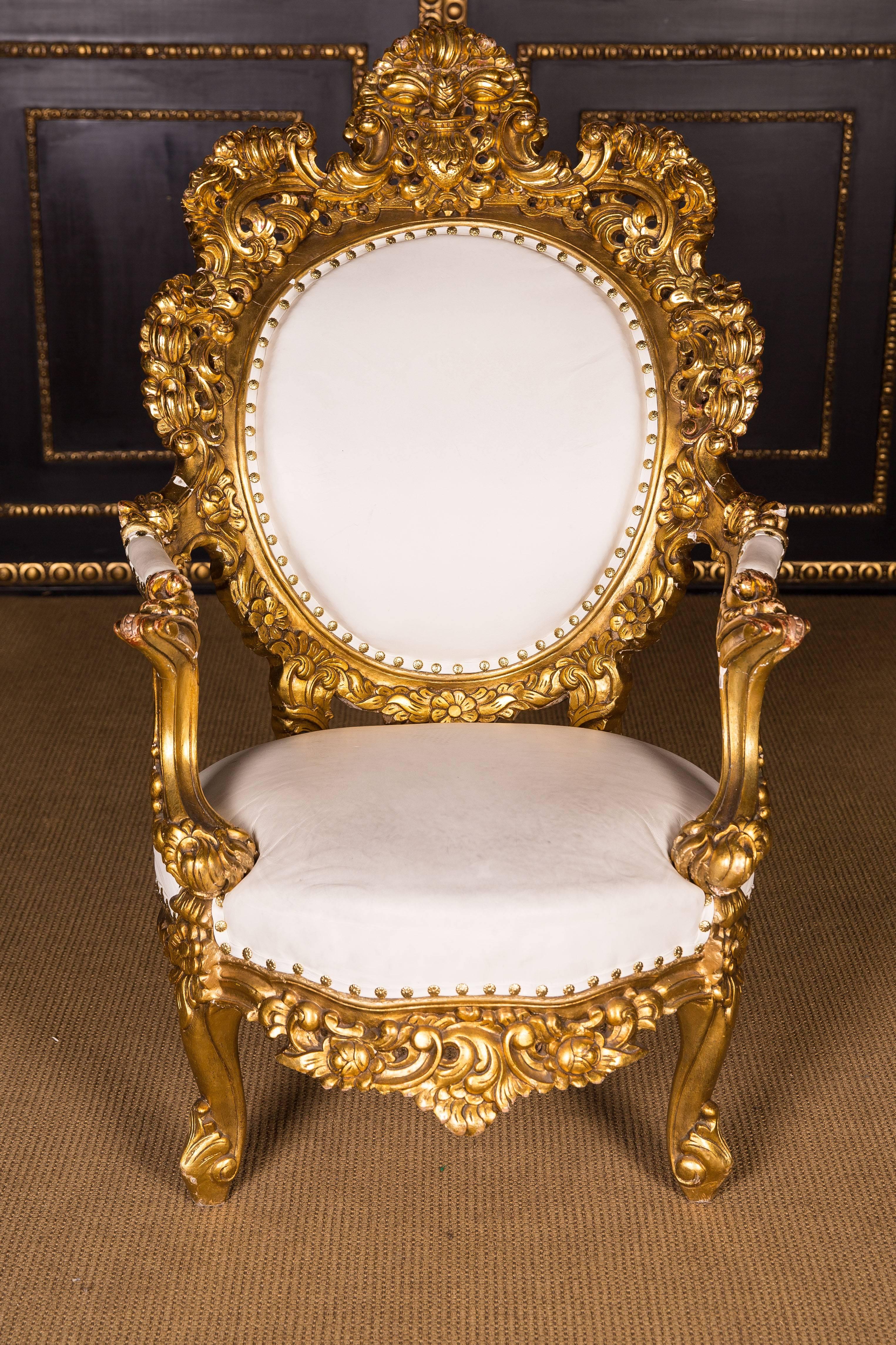 Pompouss massive beechwood, polished. Gold leaf, passively curved, profile-framed frame on curved legs. Short supports for slightly rising armrests. Shield-shaped backrest frame with floral carving. The seat and the backrest are finished with a