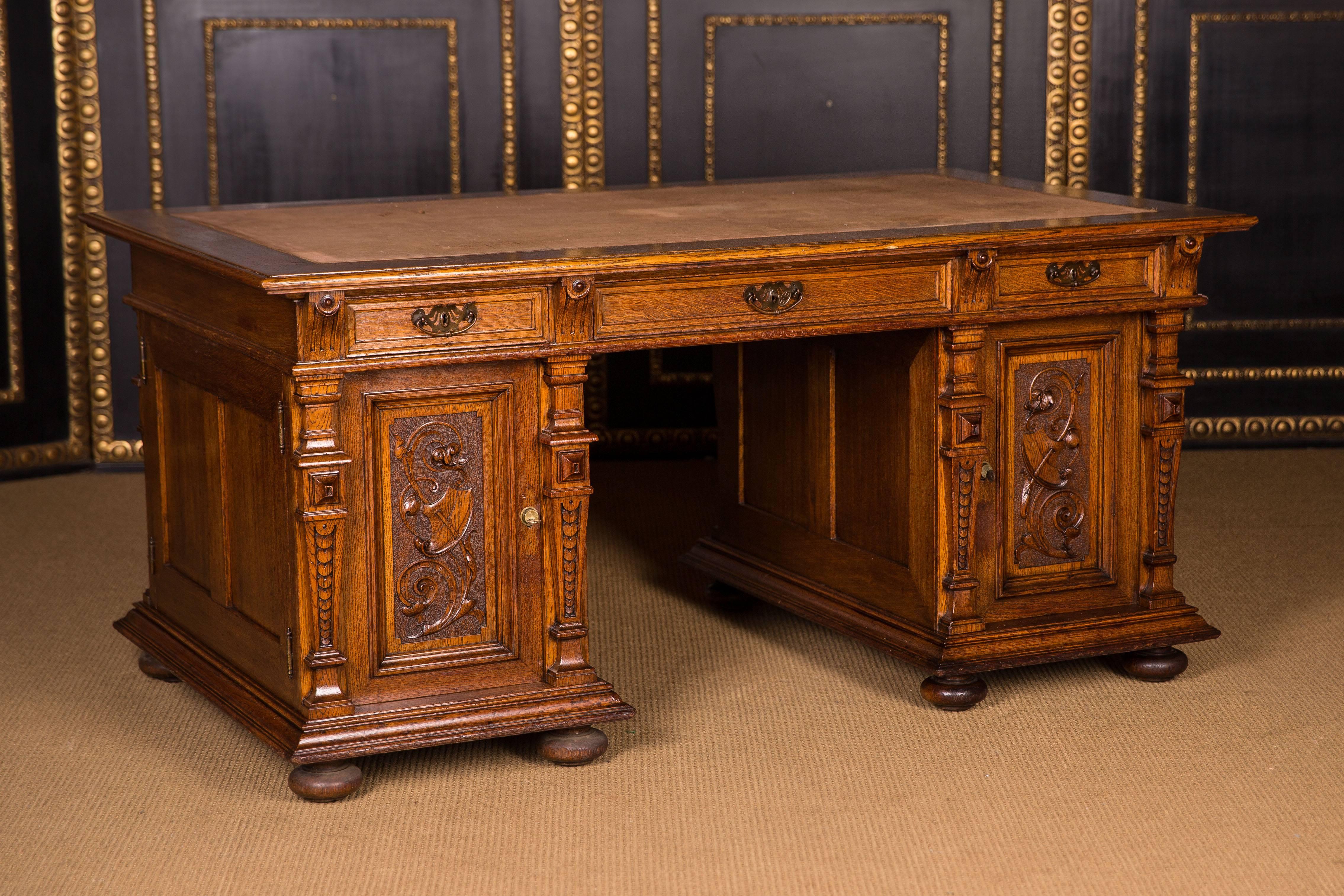 Also-called partner desk. On both sides with doors and drawers.

Solid oak. Rich carved desk. Three-part straight frame base. Slightly overlapping writing plate. Three drawers of different sizes, with a wide knee pocket. Flanked on both sides by