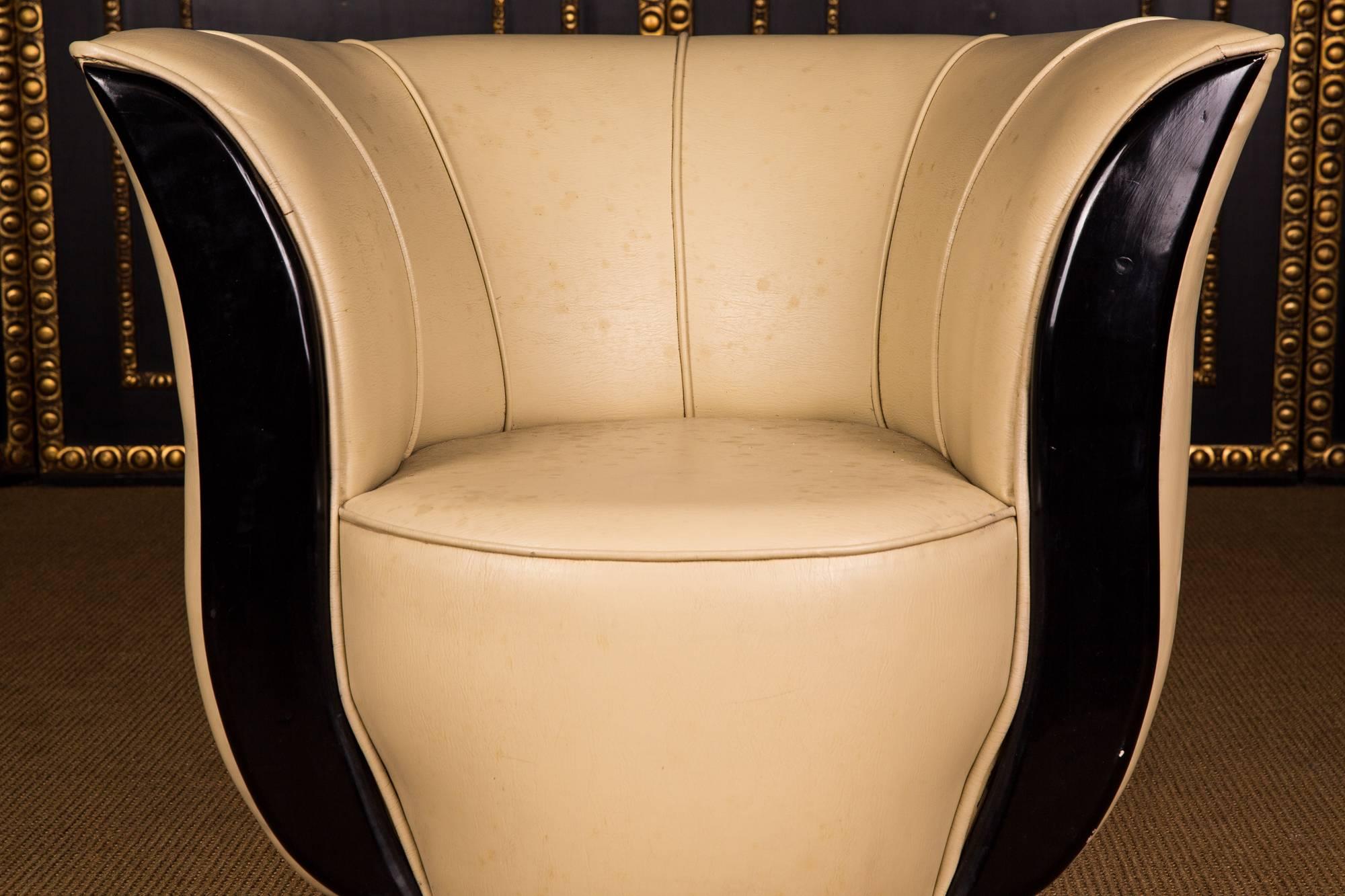 On round black base, high seating flanked by two blackened pointed wooden frames. Backrest leaning backwards. The leatherette is blotchy and must be changed or maybe you can clean it.