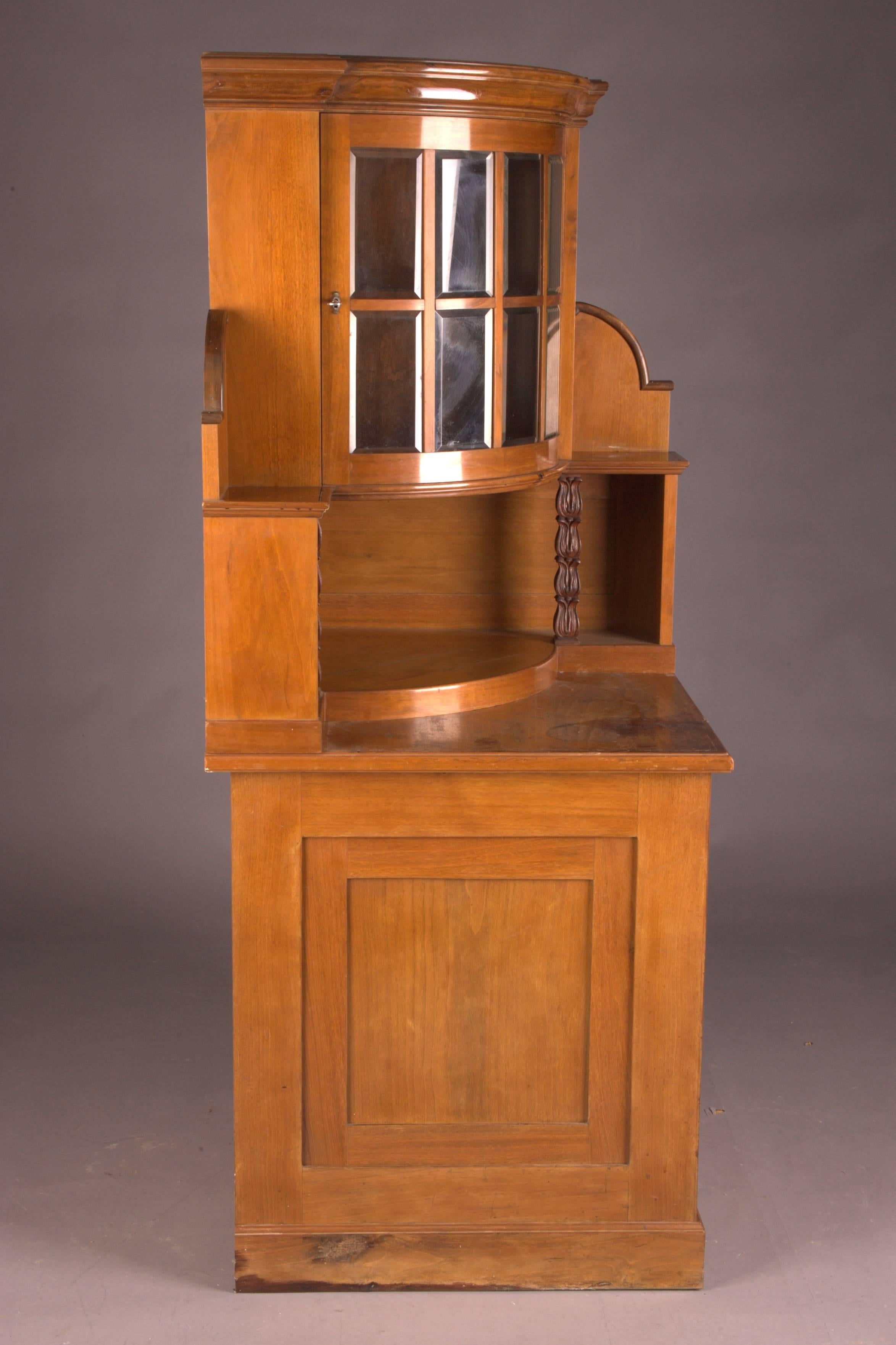 Gorgeous light and simple walnut on solid conifer. Consisting of two parts. The lower part has a door with cassette filling. Behind it is a storage area. Slightly protruding top plate. Restored essay, supported by two filigree carved columns. A
