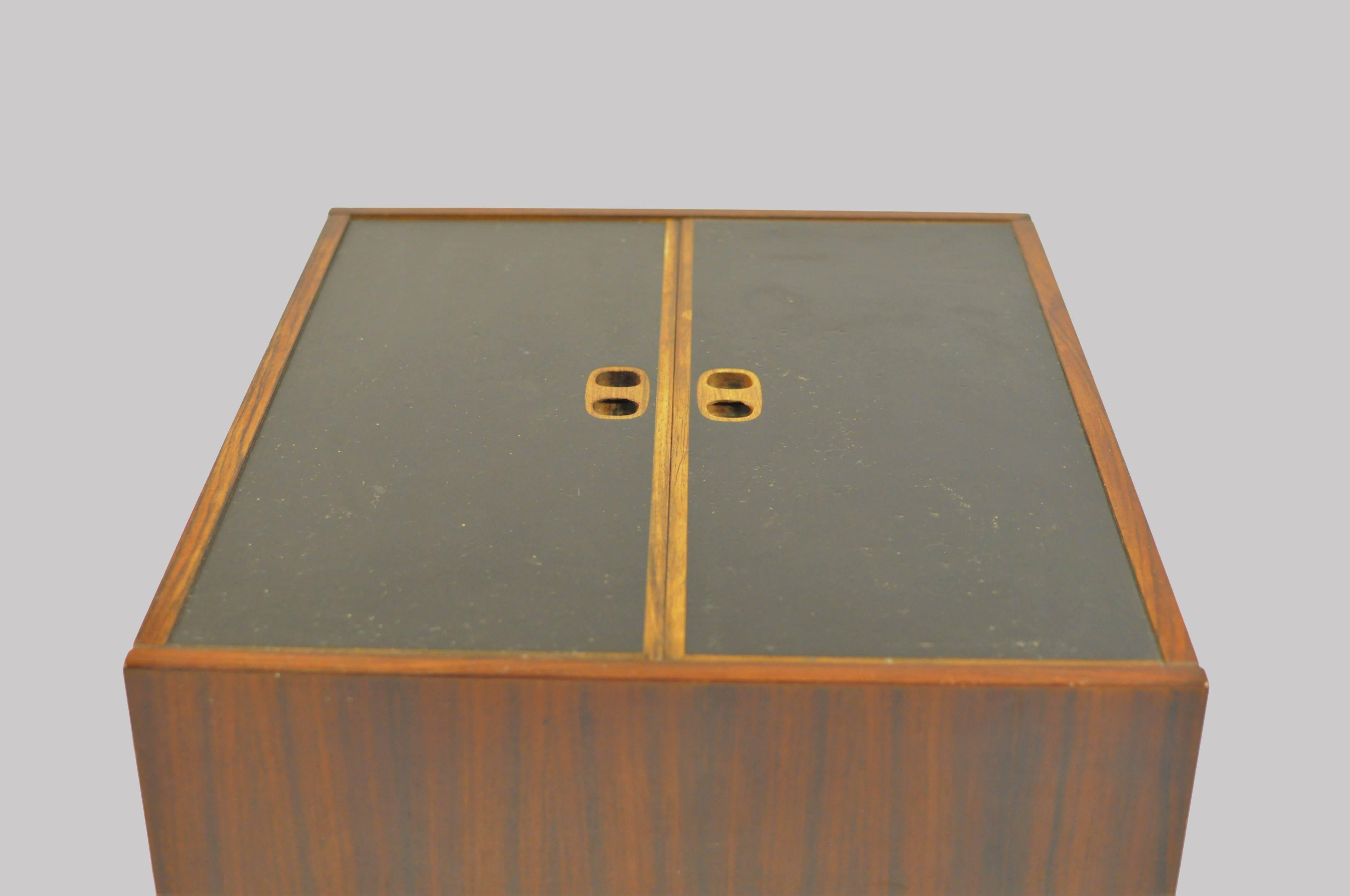 1960s Danish Modern folding bar cabinet in rosewood and black formica from Randers Møbelfabrik.

The cabinet is well designed and will fit in easily where you need it both as a small sidetable when folded or as a small bar where you can easily see