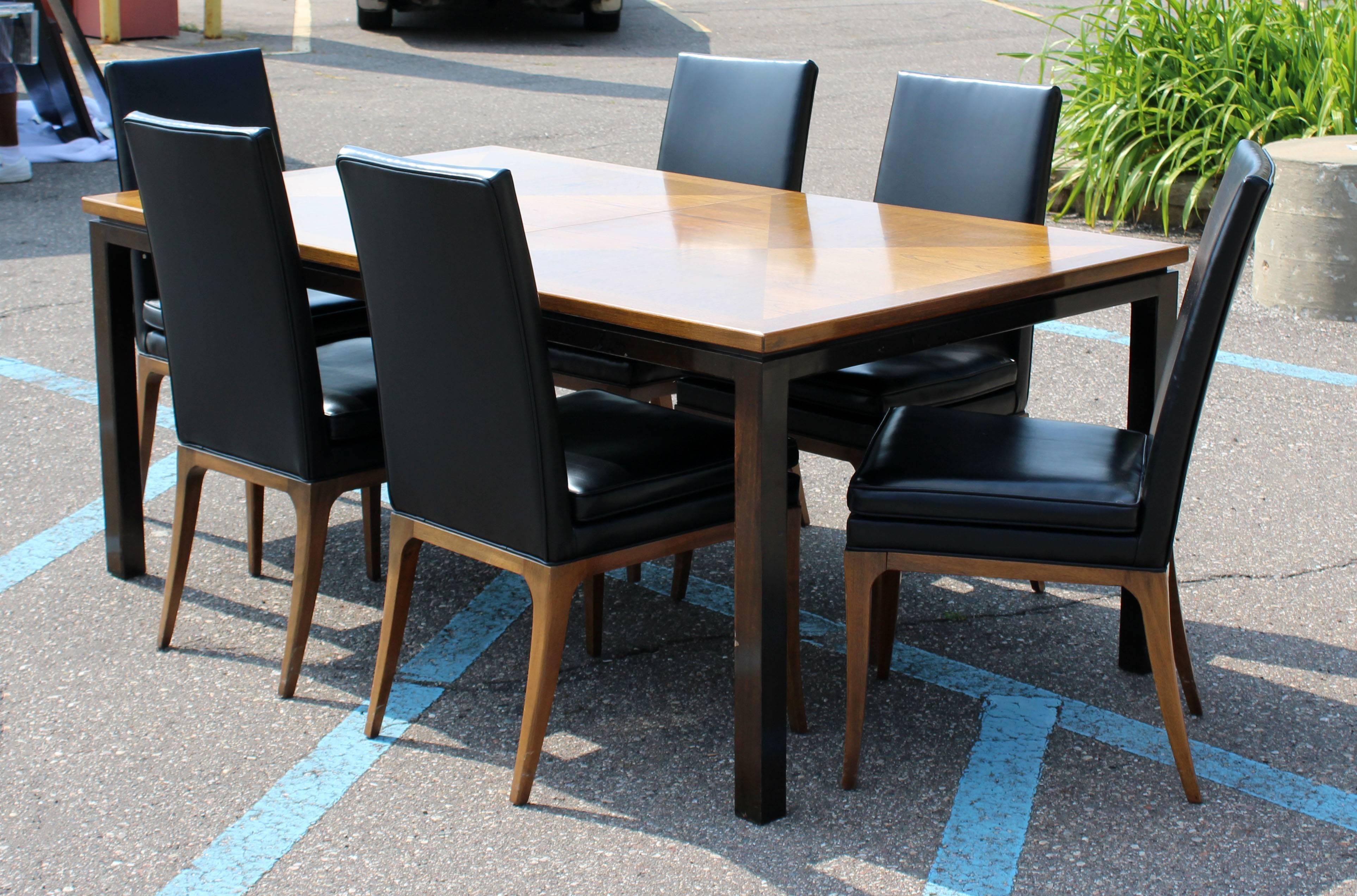 For your consideration is a fantastic dining set from the 1950s by Harvey Probber. The incredible walnut and mahogany parsons style table has three leaves and the six dining chairs are covered in black vinyl. In excellent condition. The dimensions