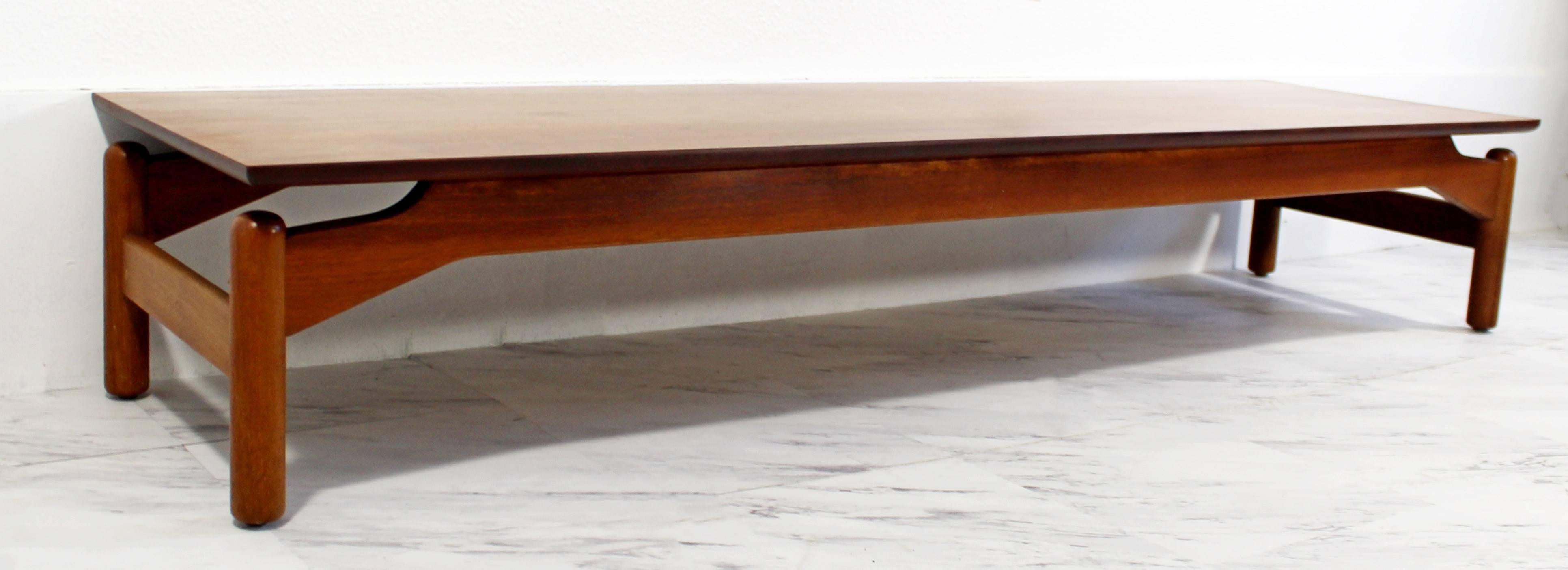 For your consideration is a long low walnut coffee table by Greta Grossman for Glenn of California. The table has a flat plane top that floats above four rounded dowel legs and is supported by an arched frame. n excellent condition. The dimensions