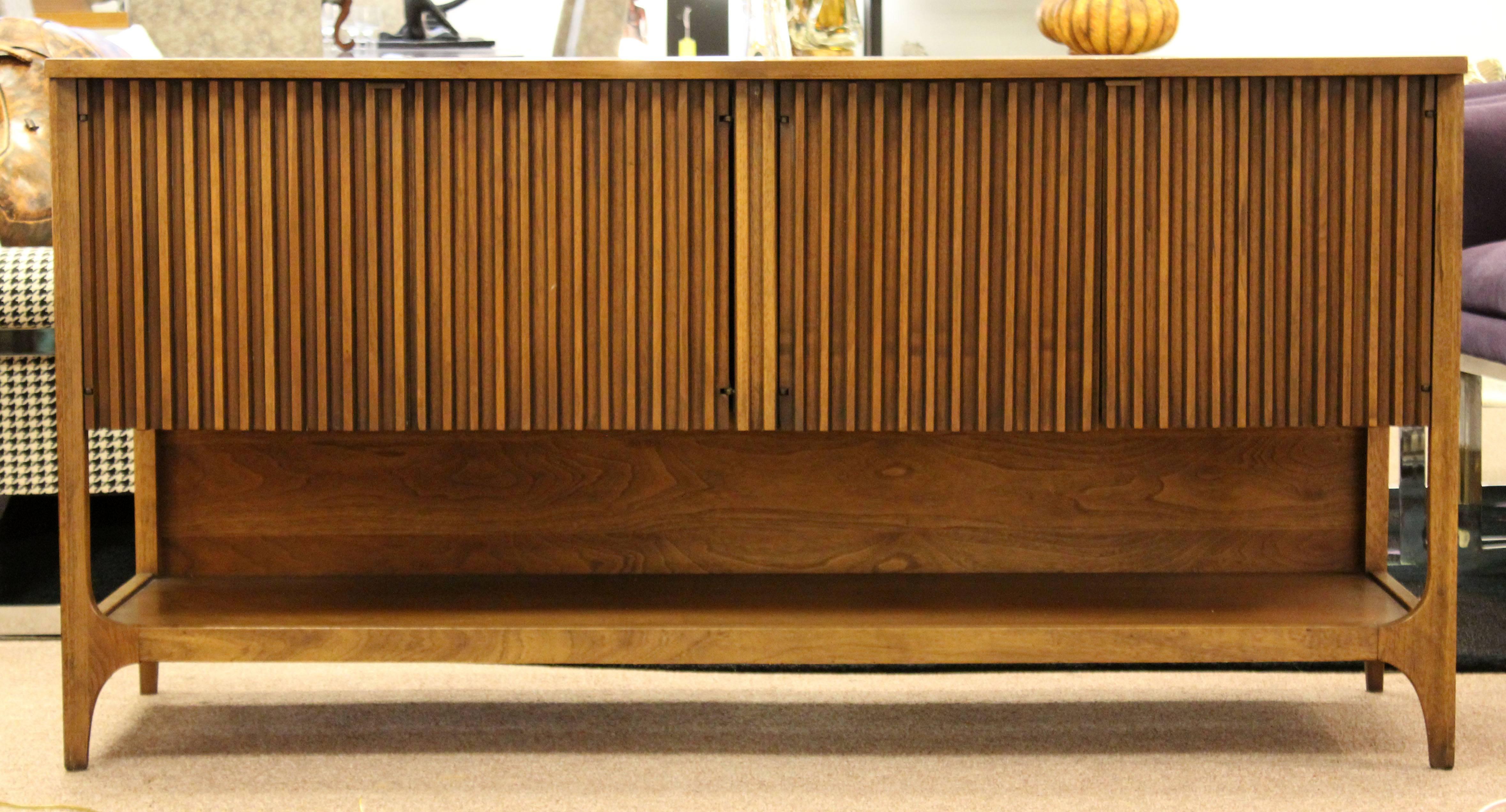 For your consideration is a lovely, short credenza, with tambour styled doors that open outward, from the Brasilia Collection by Broyhill Premier. In excellent condition. The dimensions are 60