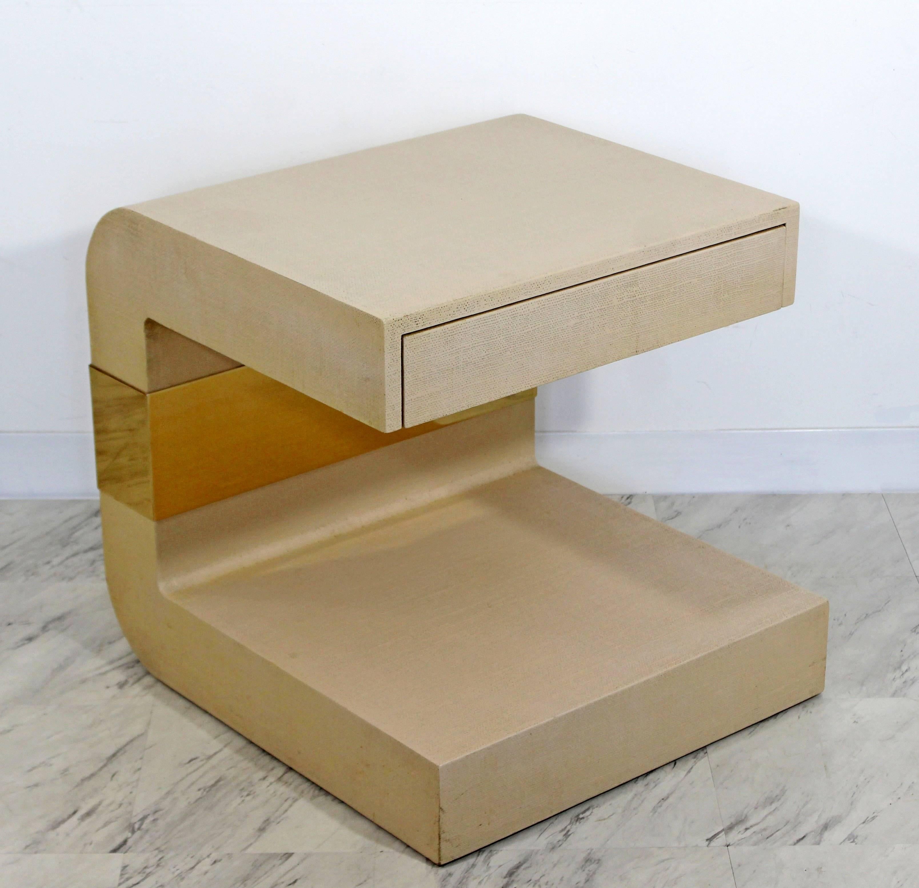 For your consideration is a stunning, sculptural side or end table, with one drawer, made of grasscloth and brass, attributed to Karl Springer, circa the 1970s. In excellent condition. The dimensions are 22