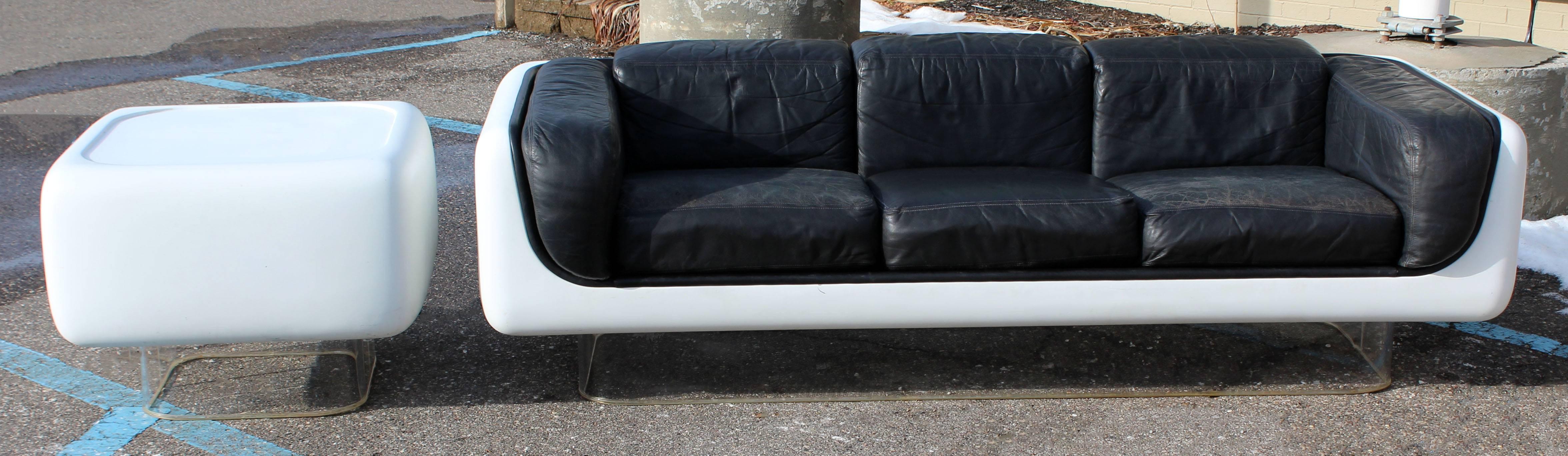 For your consideration is a rare William Andrus for Steelcase, chic and cool, fiberglass floating sofa on a Lucite base with original leather with the perfect age patina to the leather. Also comes with matching fiberglass and Lucite end table, circa