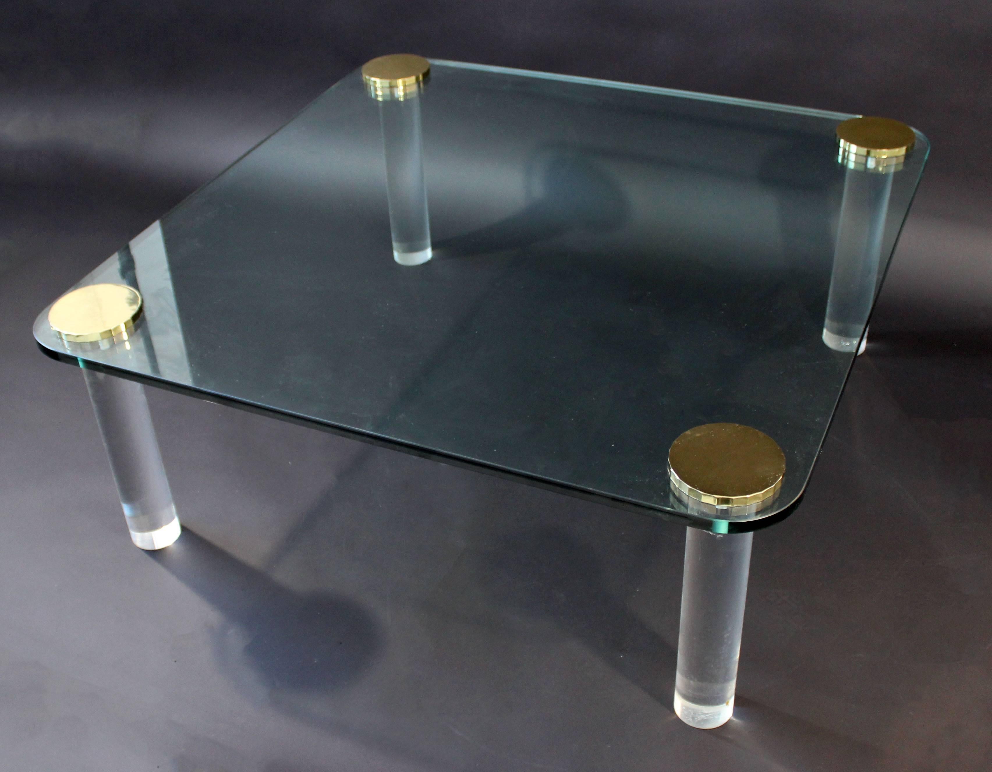 For your consideration is a fabulously chic coffee table, brass caps with a rounded edge, square glass top and round Lucite legs. Circa the 1970s. In excellent condition. The dimensions are 42