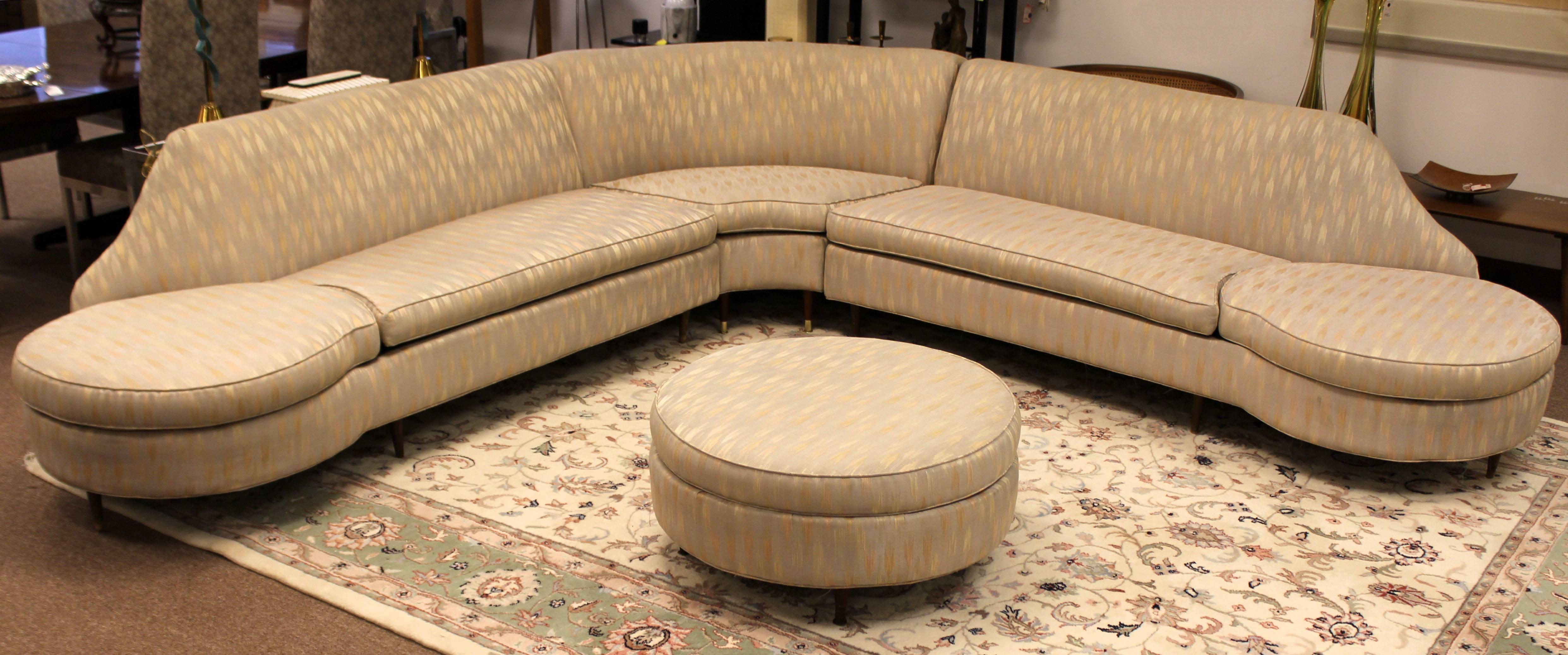 For your consideration is a quirky and unique, curved, three-piece, sectional sofa on wooden legs. The end cushions and that of the ottoman remove to reveal built-in side tables. Attributed to custom Dunbar. In great condition. The dimensions of