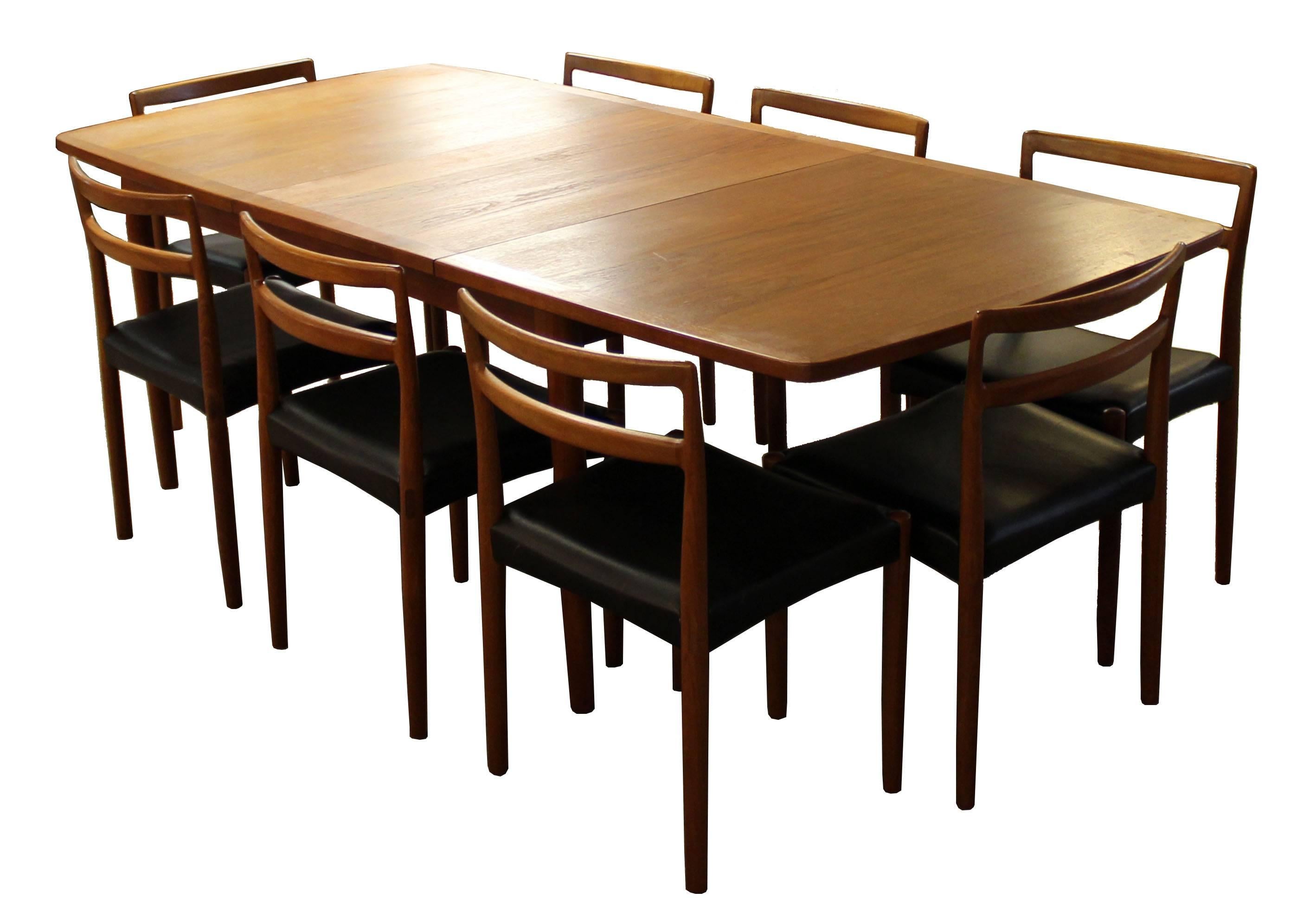 For your consideration is a phenomenal, teak, dining set, including an expandable table with two leafs and eight side, dining chairs, with black faux leather seats, by Norwegian company Illums Bolighus, circa the 1950s. In excellent condition. The