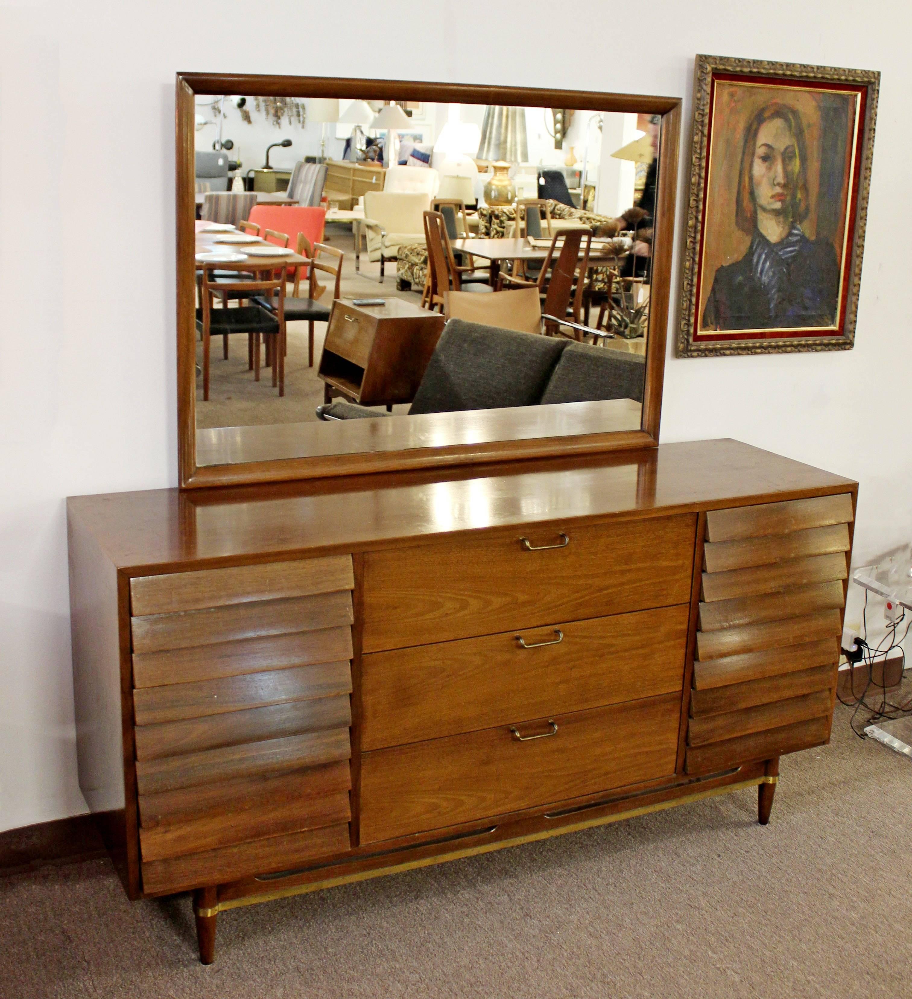 For your consideration is a stunning, walnut dresser and mirror, designed by Merton Gershun for American of Martinsville, the Dania collection, circa the 1970s. The dresser has nine louvered drawers, brass trim and sculpted handles. In excellent