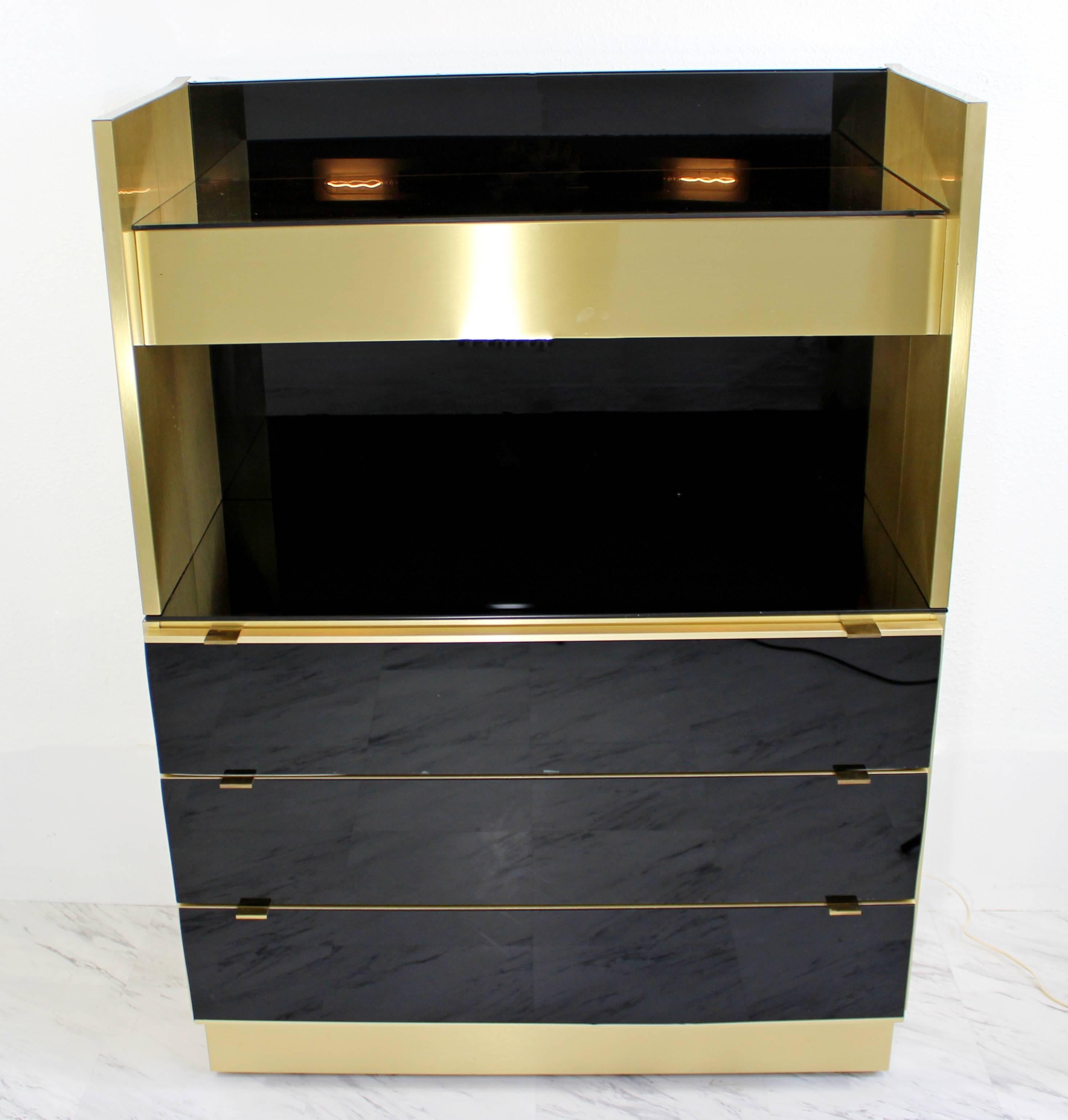 For your consideration is an incredibly sexy, standing two-piece dry bar, made of brass, smoked glass and mirror, with two lights under the top shelf and three drawers on the bottom. In great condition. The dimensions are 36
