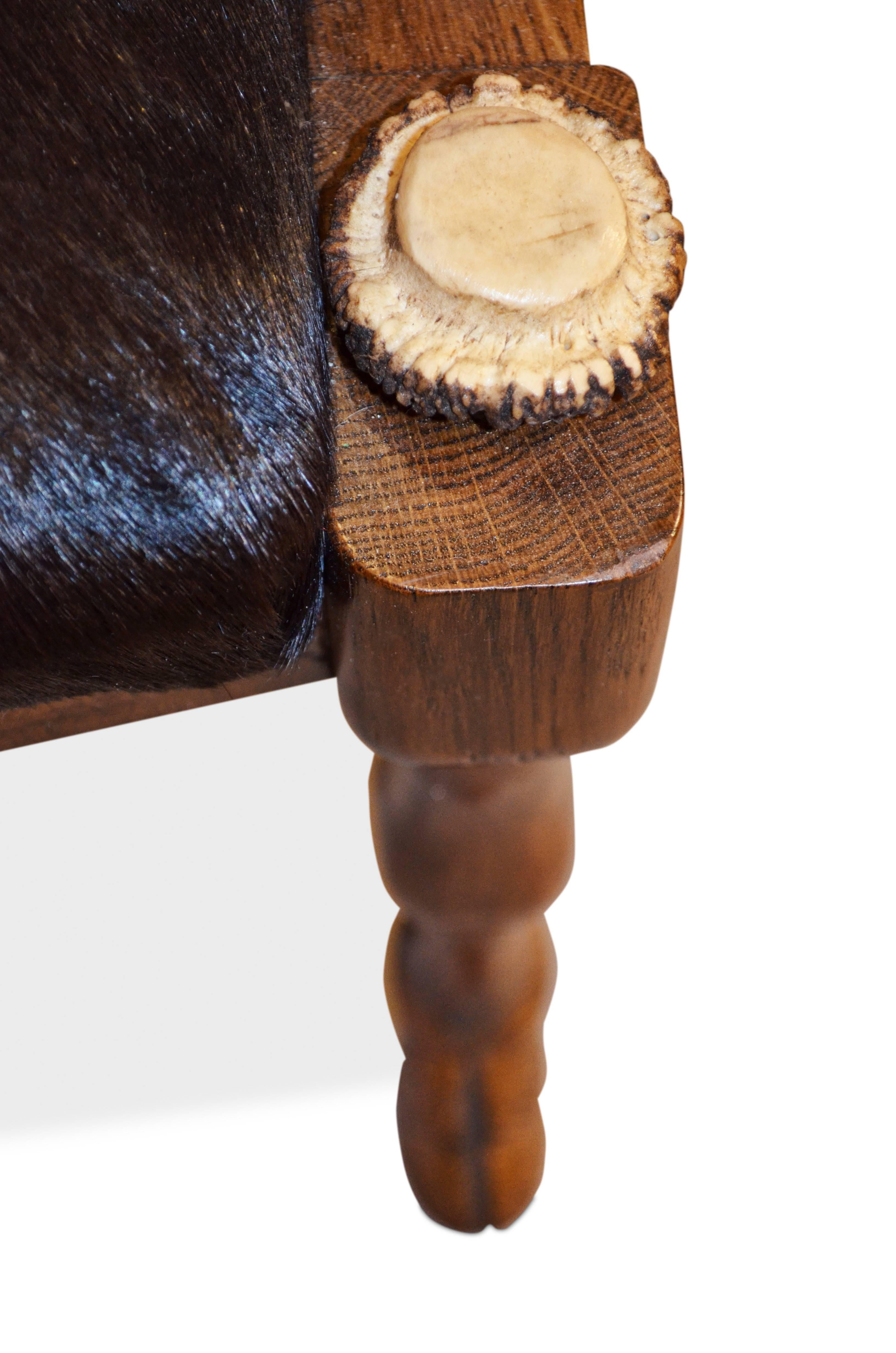 A pair of Anthony Redmile European fallow deer antler chairs, cowhide covered seat on beautifully carved detailed oak hoof feet.