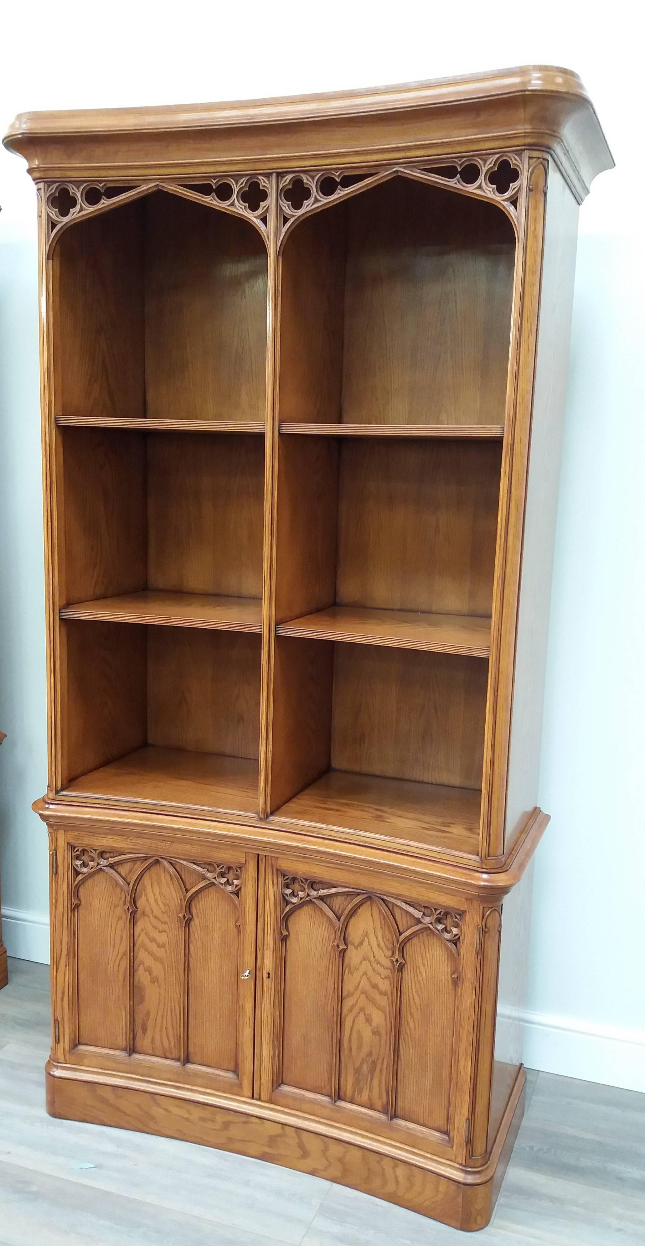 Inspired by a revivalist Gothic design of the 1840's, this magnificent oak bookcase features a slightly concave front and ornate tracery work to the pediment and lower cupboard doors.  The upper section is open fronted (as was the original) and