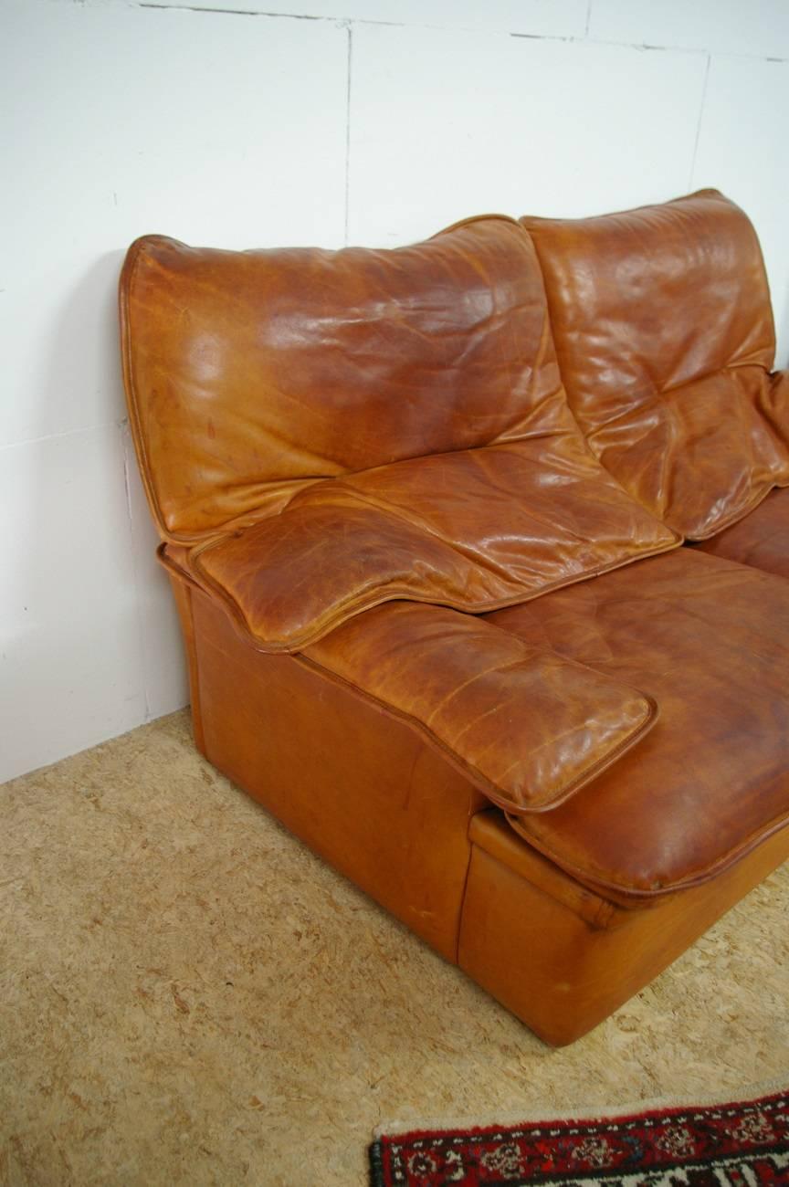 Very nice leather French design sofa from the 1970s-1980s, perfect for a game room or man cave. It has a great patine and is well finished with leather straps to secure the cushions.

The sizes are:
160 cm/62.9 wide
96 cm/37.7 deep
80 cm/31.4