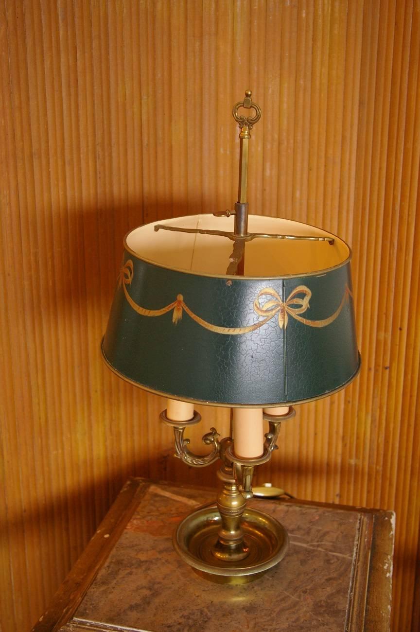 French gilded bronze bouillotte lamp with green tole painted metal shade decorated with gold-colored patterns, all in Empire style and from the 1960s-1970s. It’s in a good working condition.

The measurements are:
Depth 28 cm/ 11 inch.
Width 28