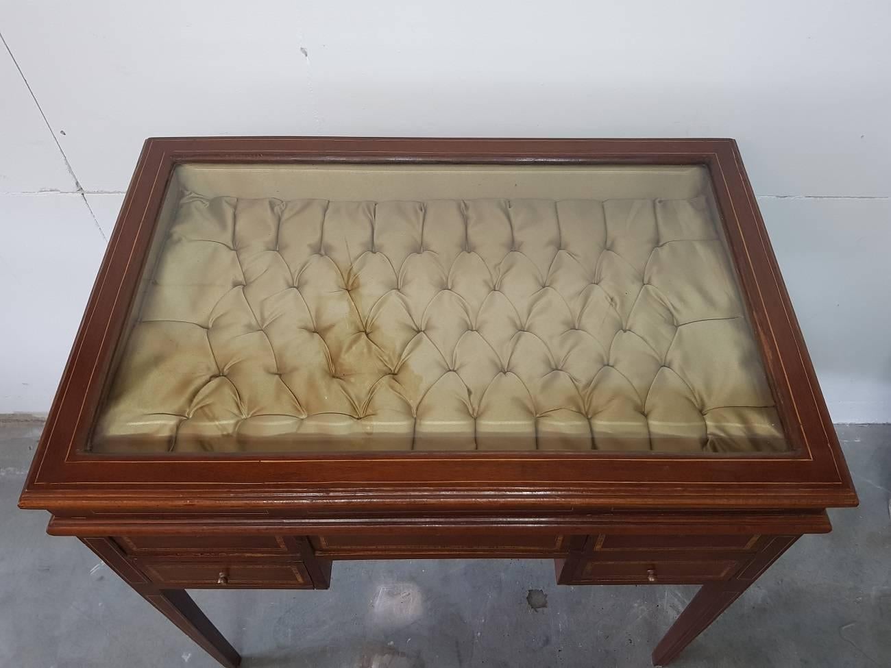 Gorgeous French Bijouterie or display or vitrine table with drawers and all around inlaid with various types of wood. It's made in the style of Charles X and has a faceted glass plate. This furniture is from the 1950s-1960s and in good condition