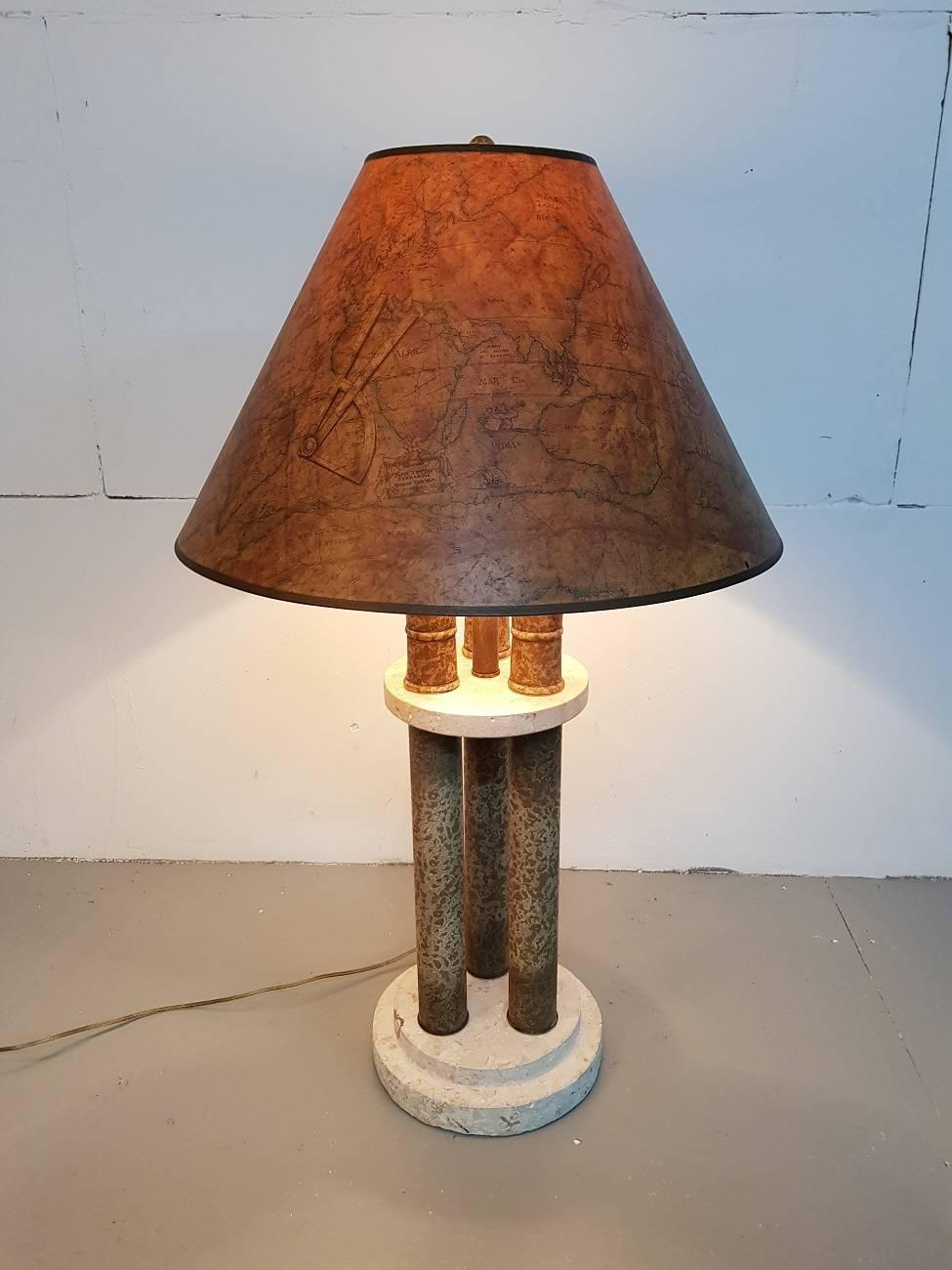 Beautiful but large table lamp from the 20th-21st century with influences from the Classical Roman and Egyptian antiquity and on the hood with a world map. The pillars are made of metal with a marble style painting with three lion heads the base is