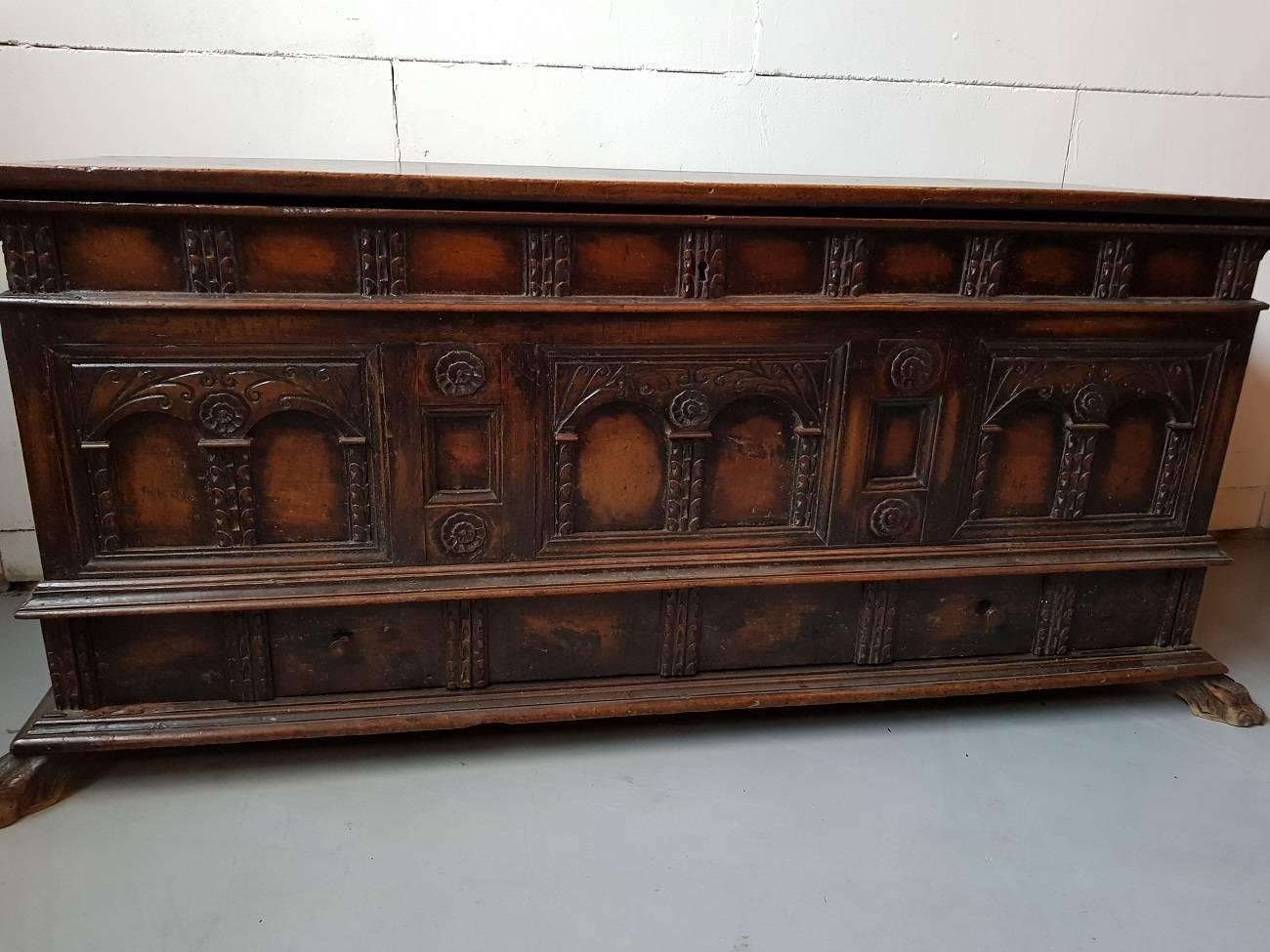 Antique carved walnut cassone coffer on paw feet from Italy, made in the 18th century, featuring beautiful carved panels on the front with paw feet at the base and a hidden drawer. This trunk can be used as a storage unit or as a bench. Excellent